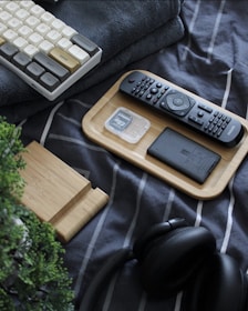 A computer keyboard, mouse, keyboard pad, and headphones on a bed