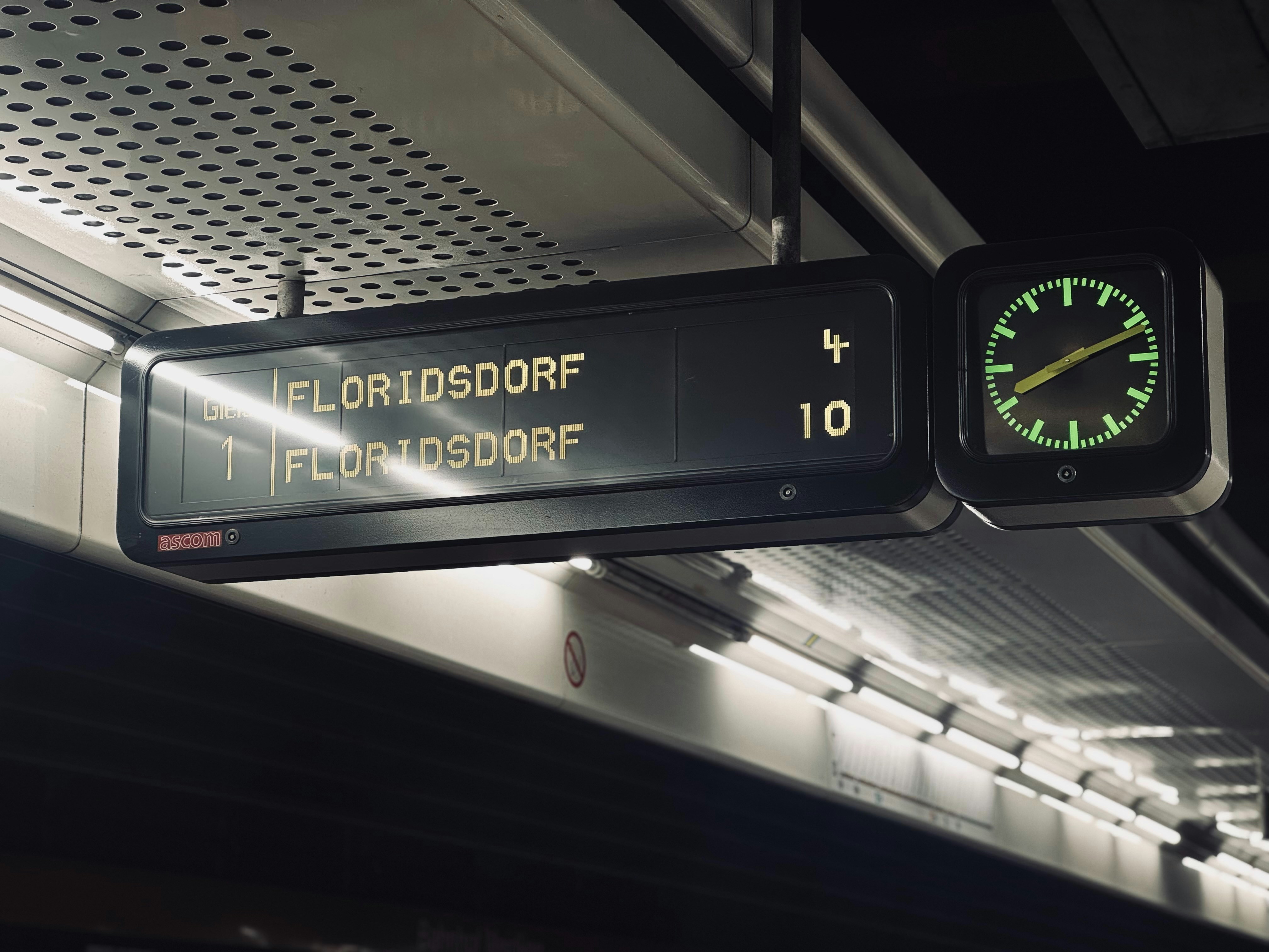 A clock hanging from the ceiling of a train station