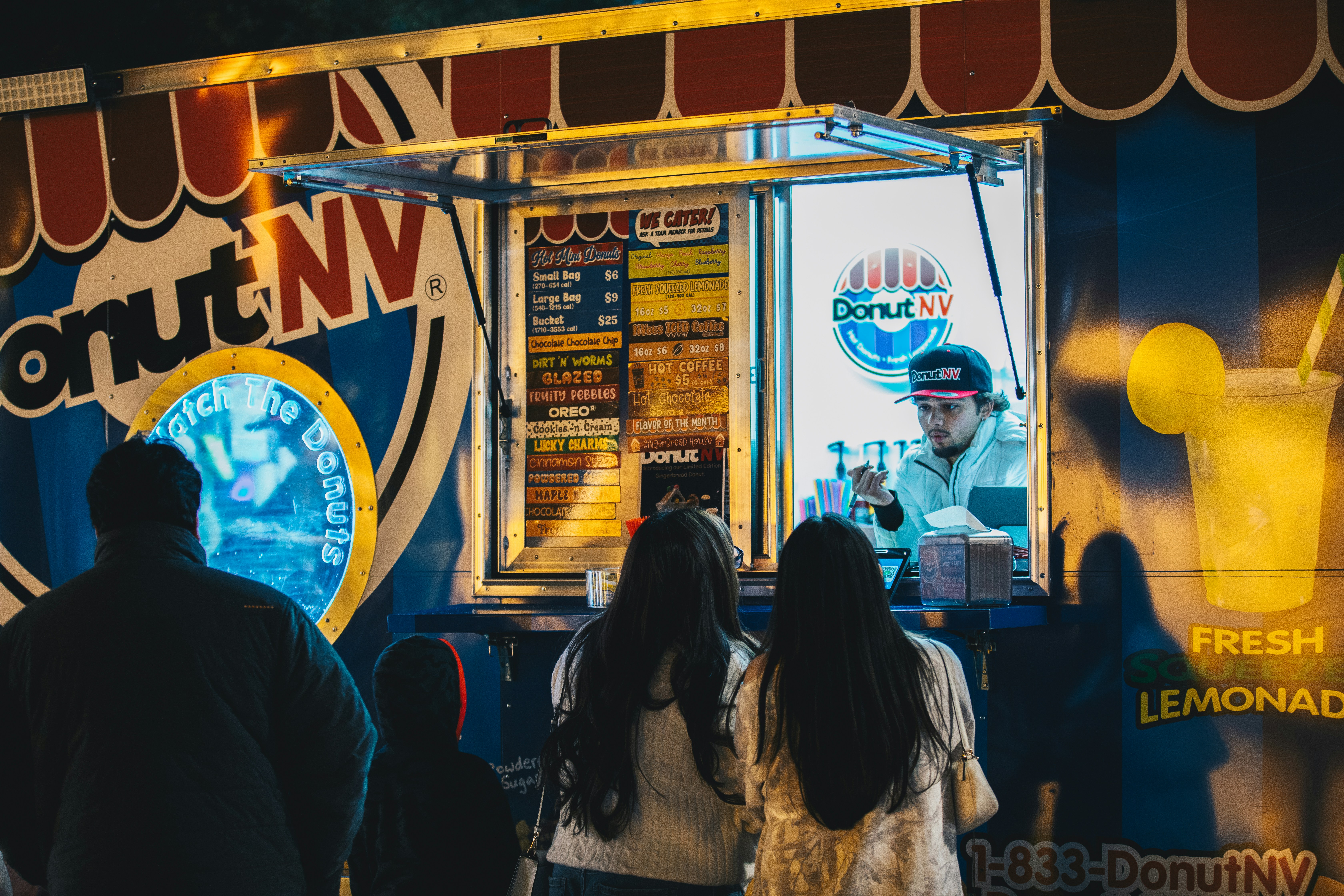 Un gruppo di persone in piedi davanti a un camion di cibo