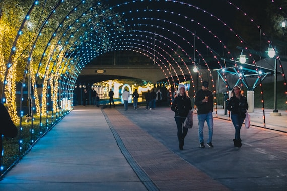 A group of people walking down a sidewalk under a tunnel