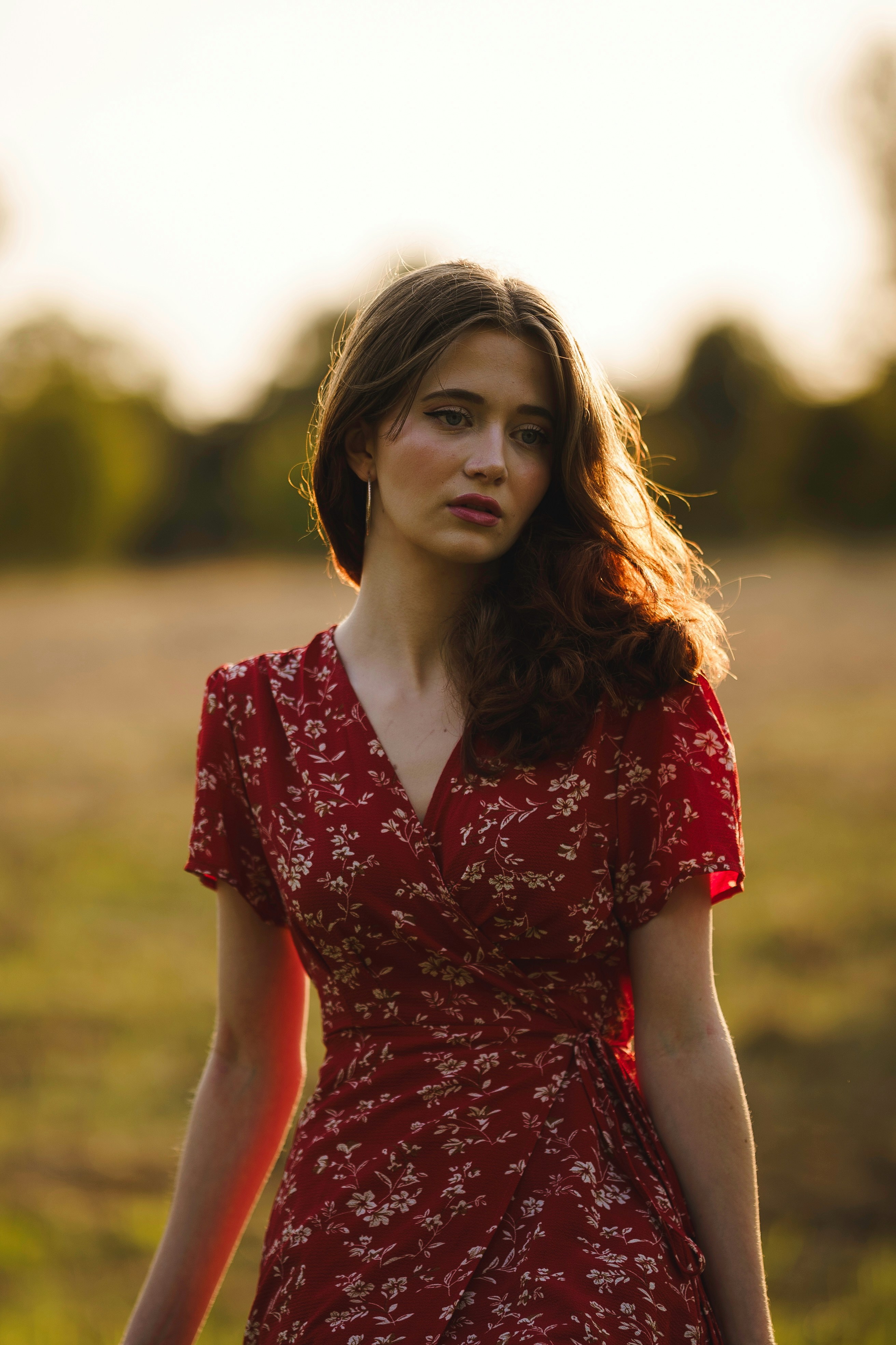 A woman in a red dress is standing in a field
