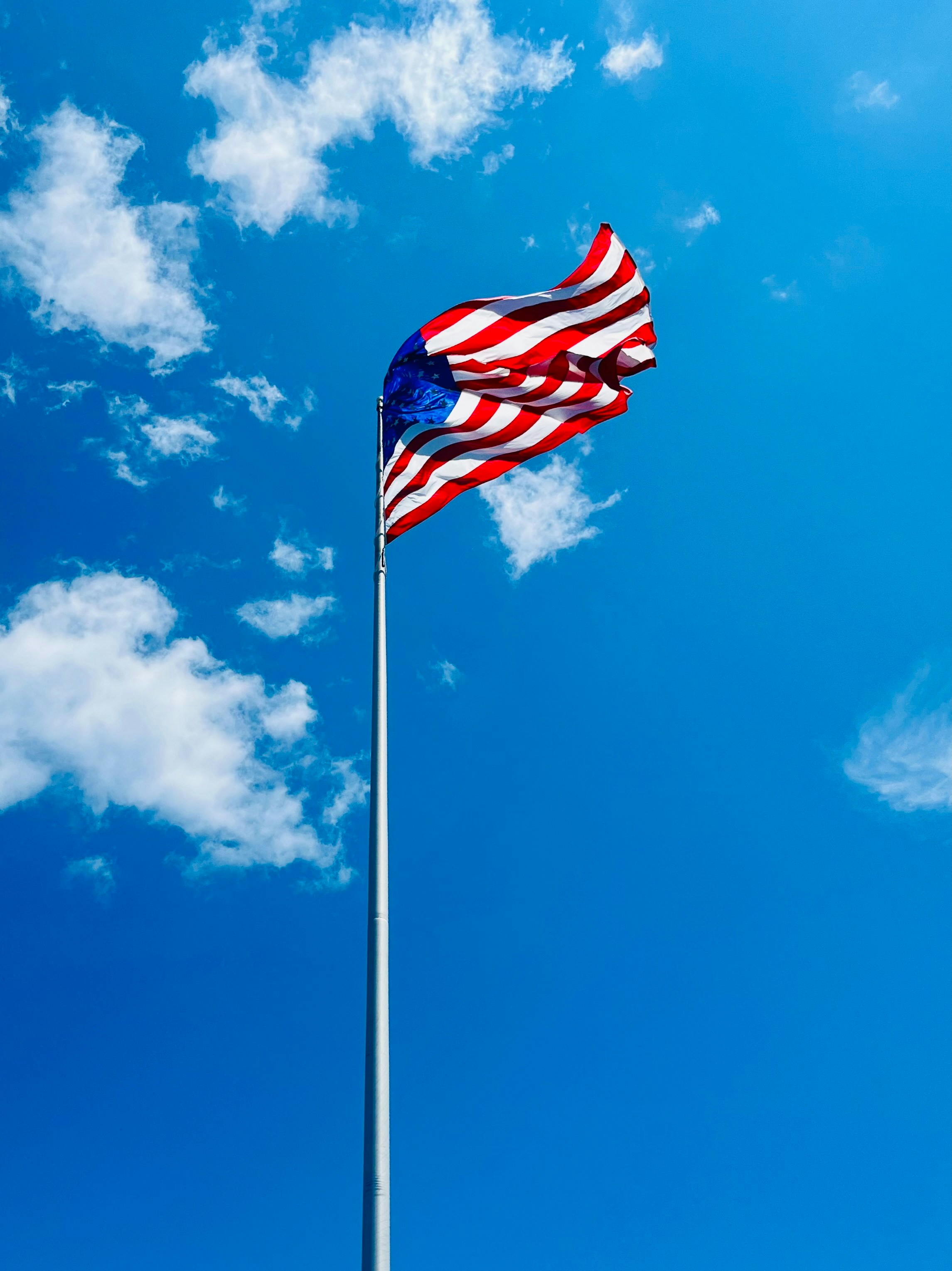 Eine amerikanische Flagge, die hoch am blauen Himmel weht