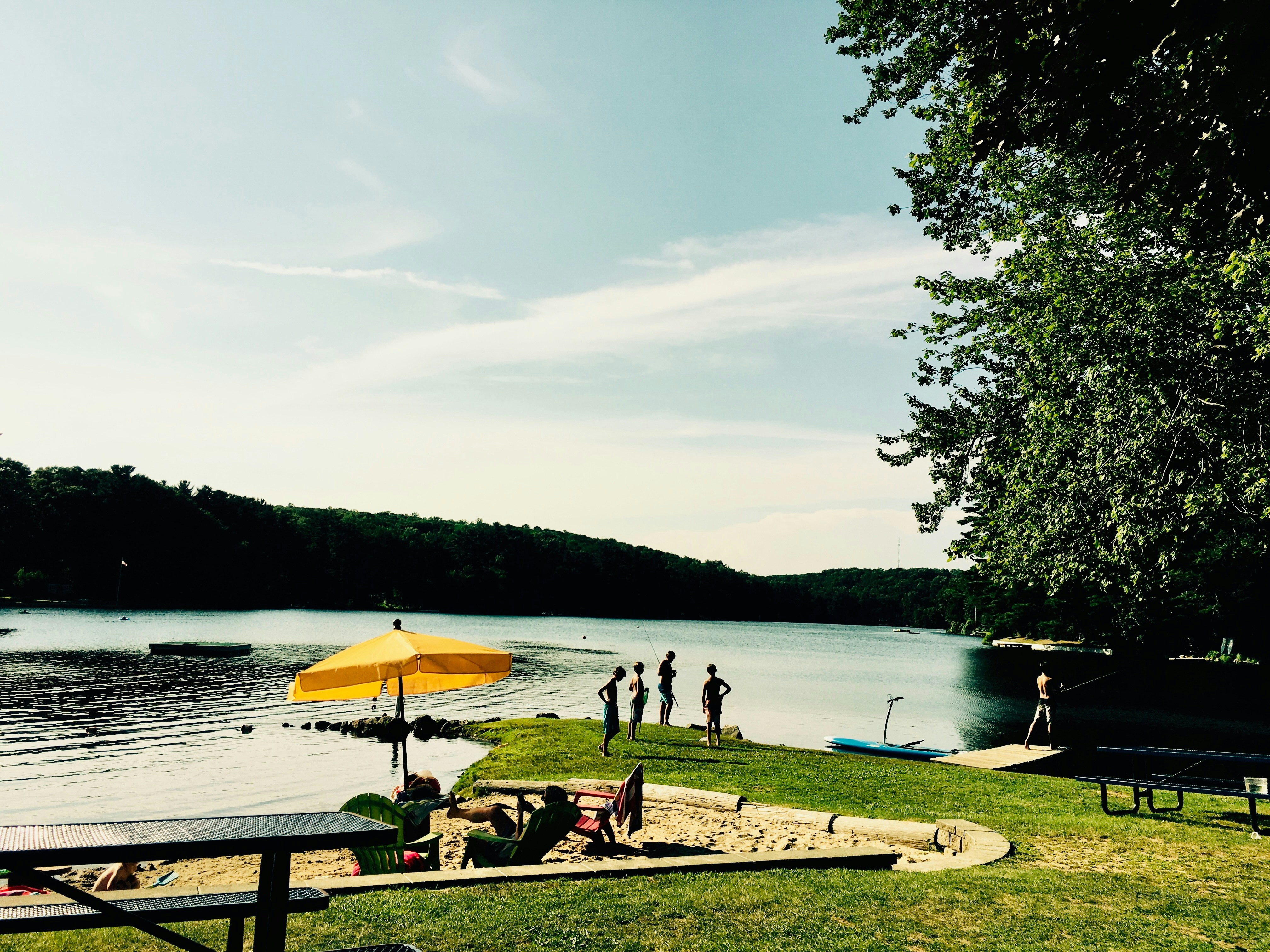 Eine Gruppe von Menschen steht auf einer saftig grünen Wiese neben einem See
