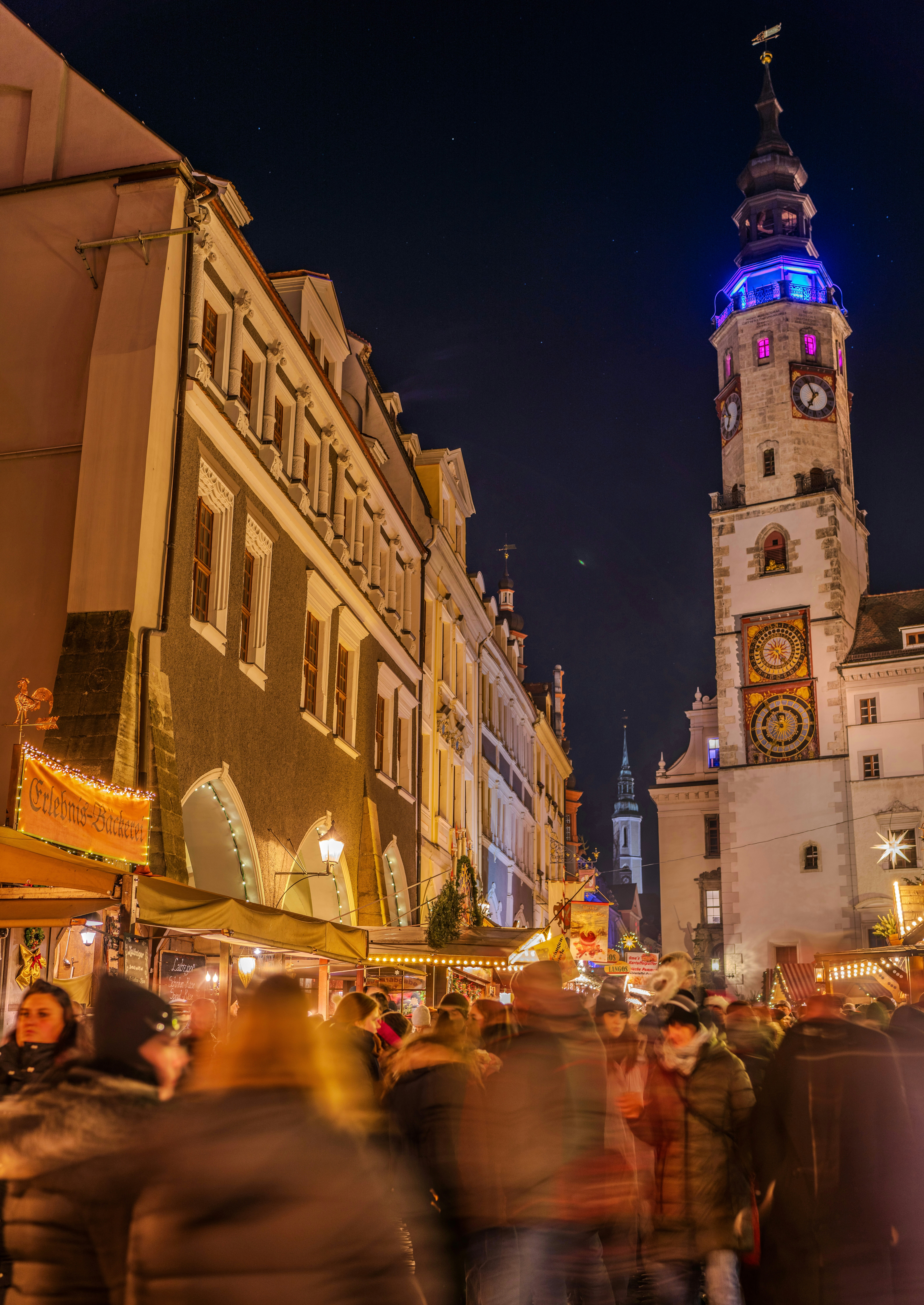A crowd of people walking down a street next to tall buildings