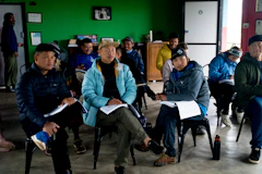 A group of adults seated in rows of chairs during an indoor briefing