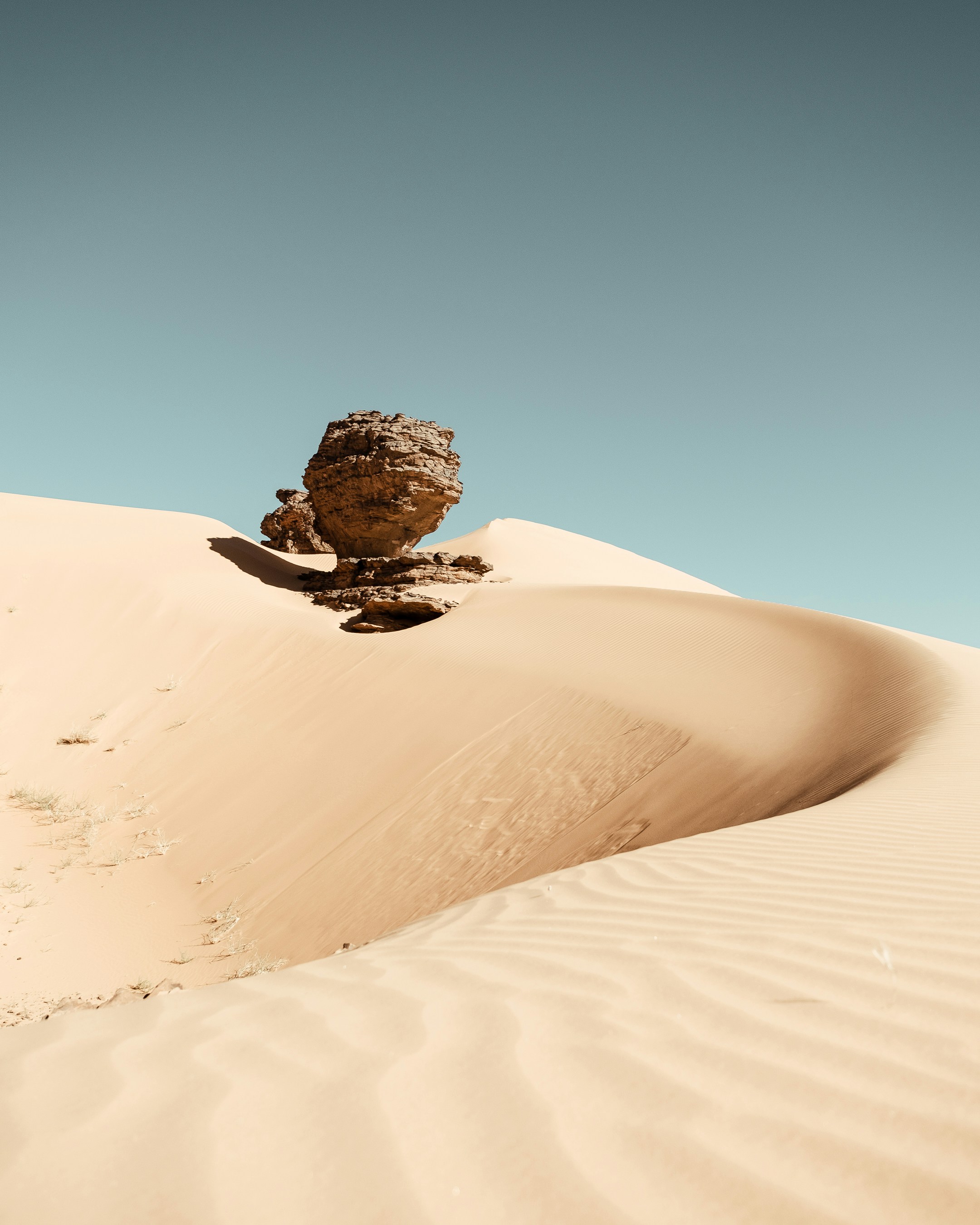 A rock sitting on top of a sandy dune