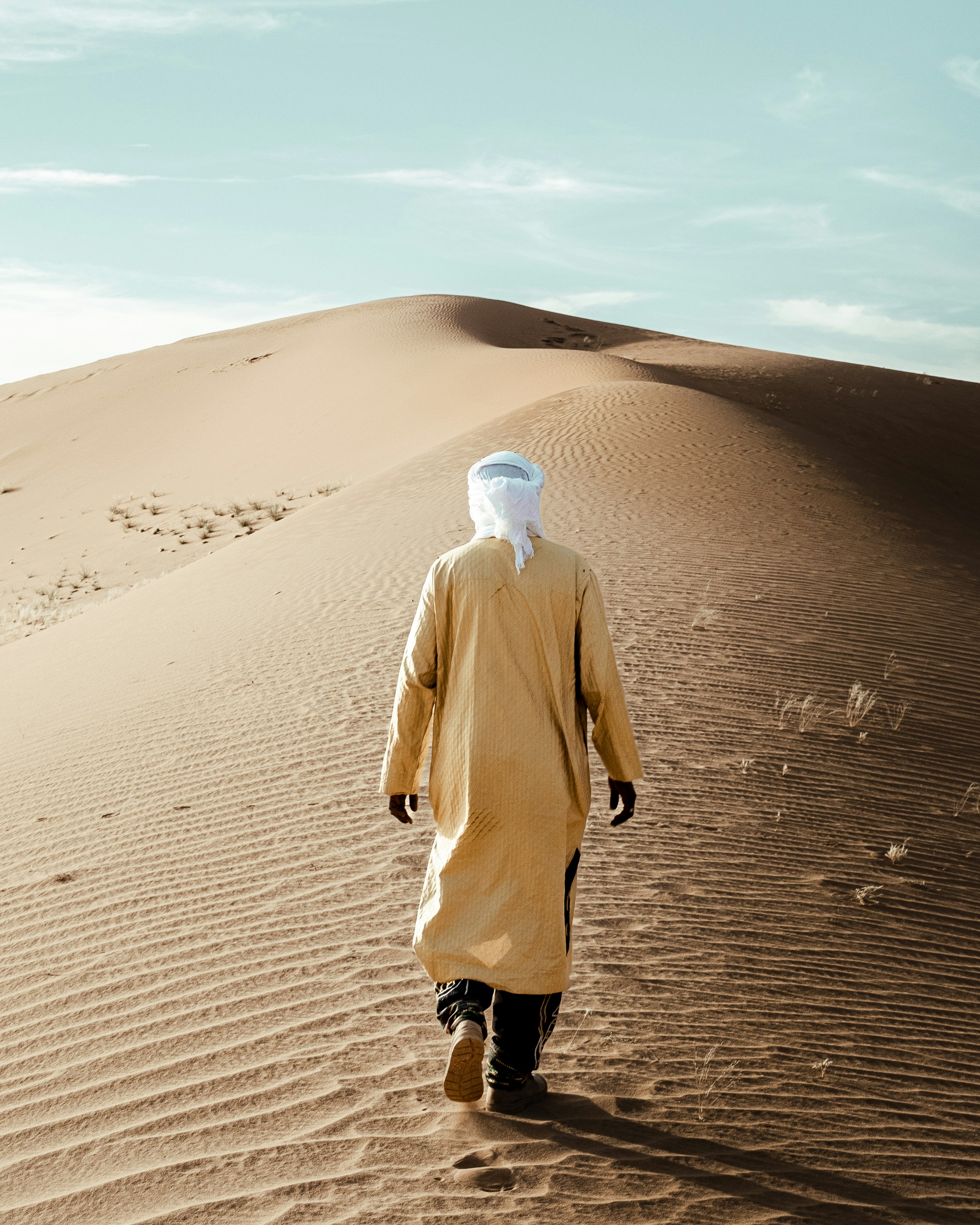 A man in a yellow outfit walking across a desert