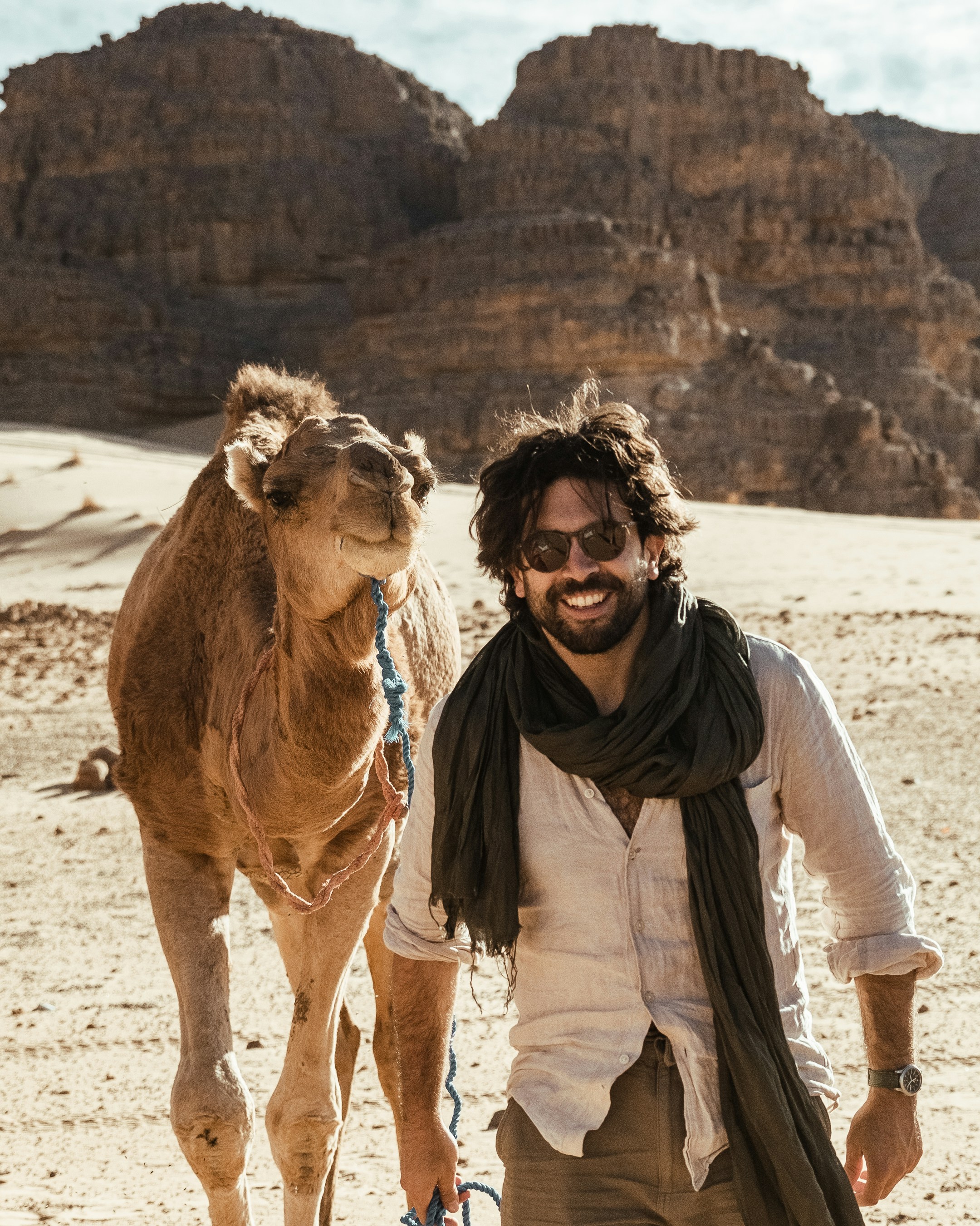 A man standing next to a camel in the desert