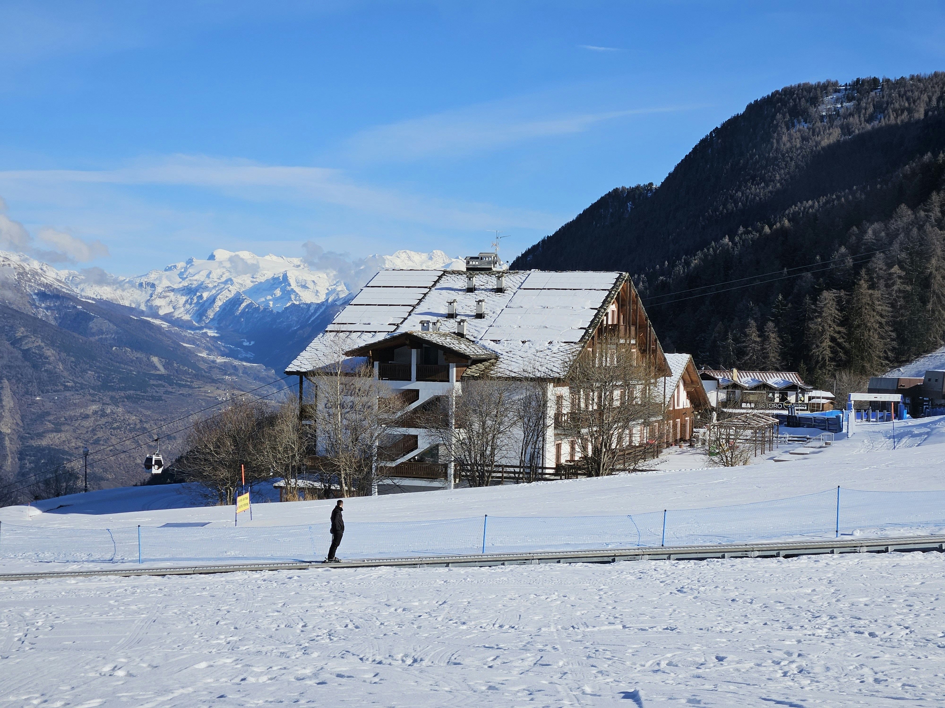 A person standing in the snow in front of a house