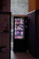 A vending machine sitting next to a window