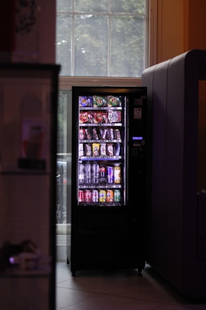 A vending machine sitting next to a window