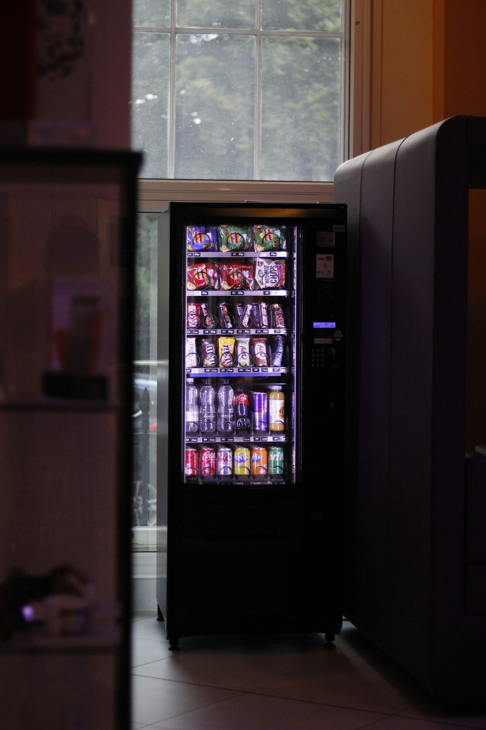 A vending machine sitting next to a window