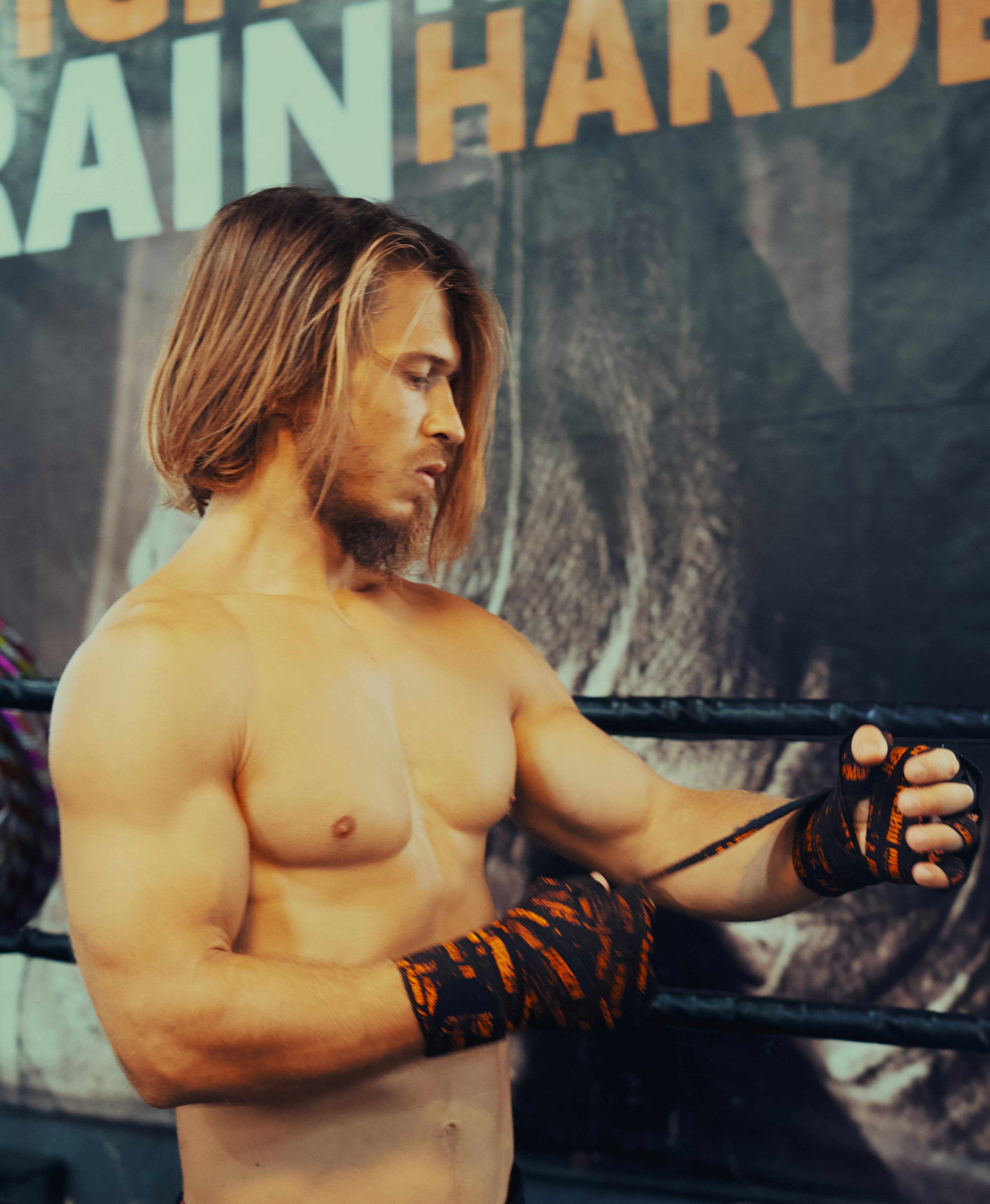 Close-up of fighter wrapping hands in white tape, bright gym