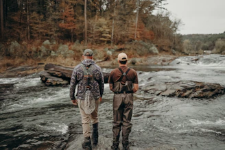 A couple of men standing on top of a river