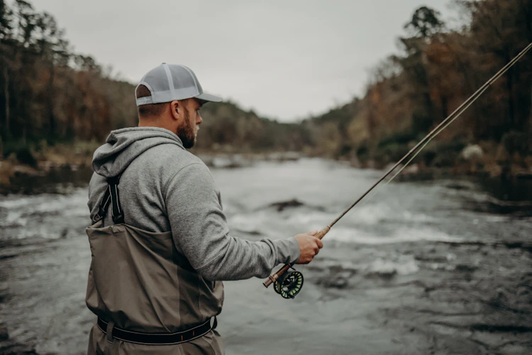 Fly angler casting on a river under a heavy overcast sky