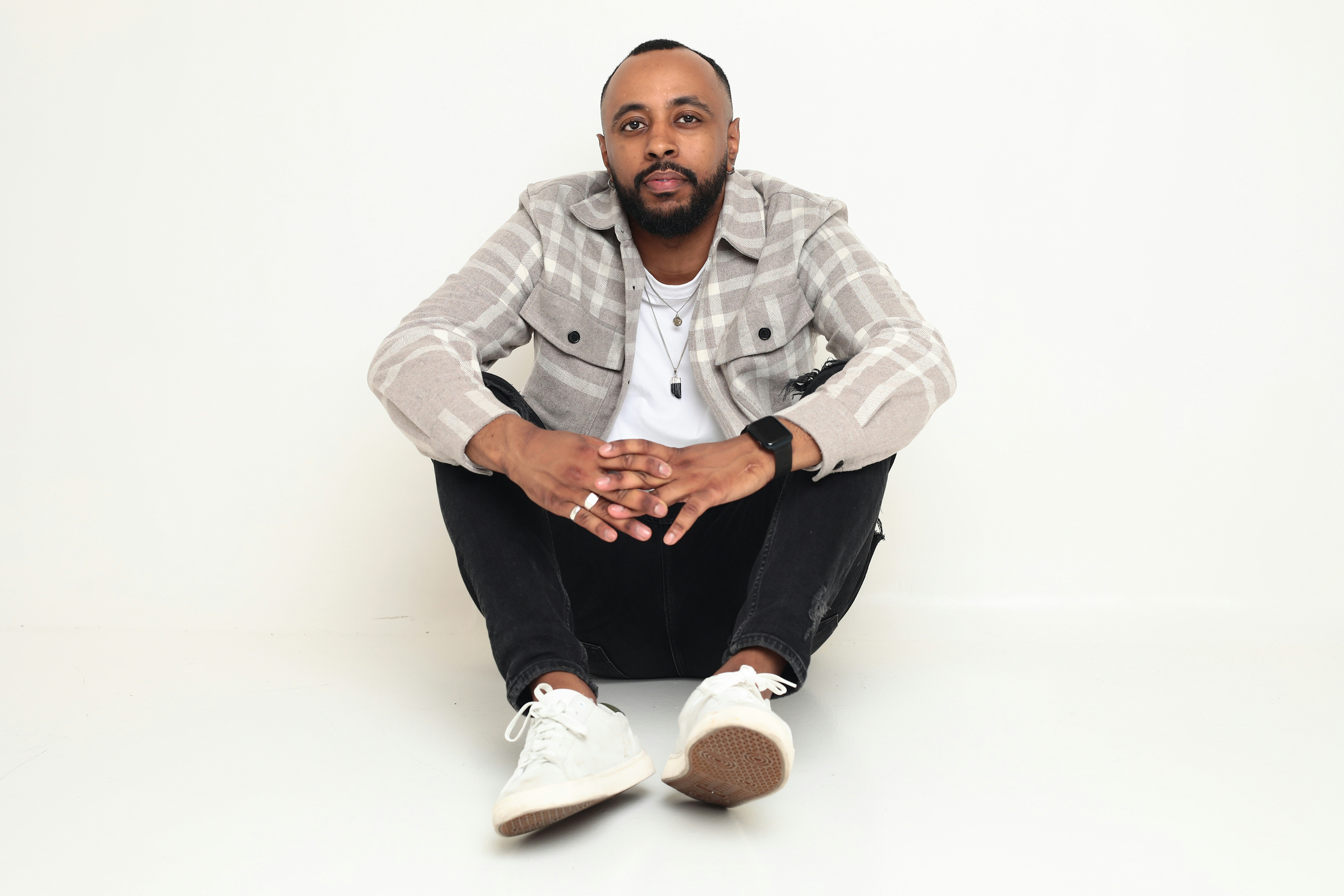 A man sitting on the floor with his hands together