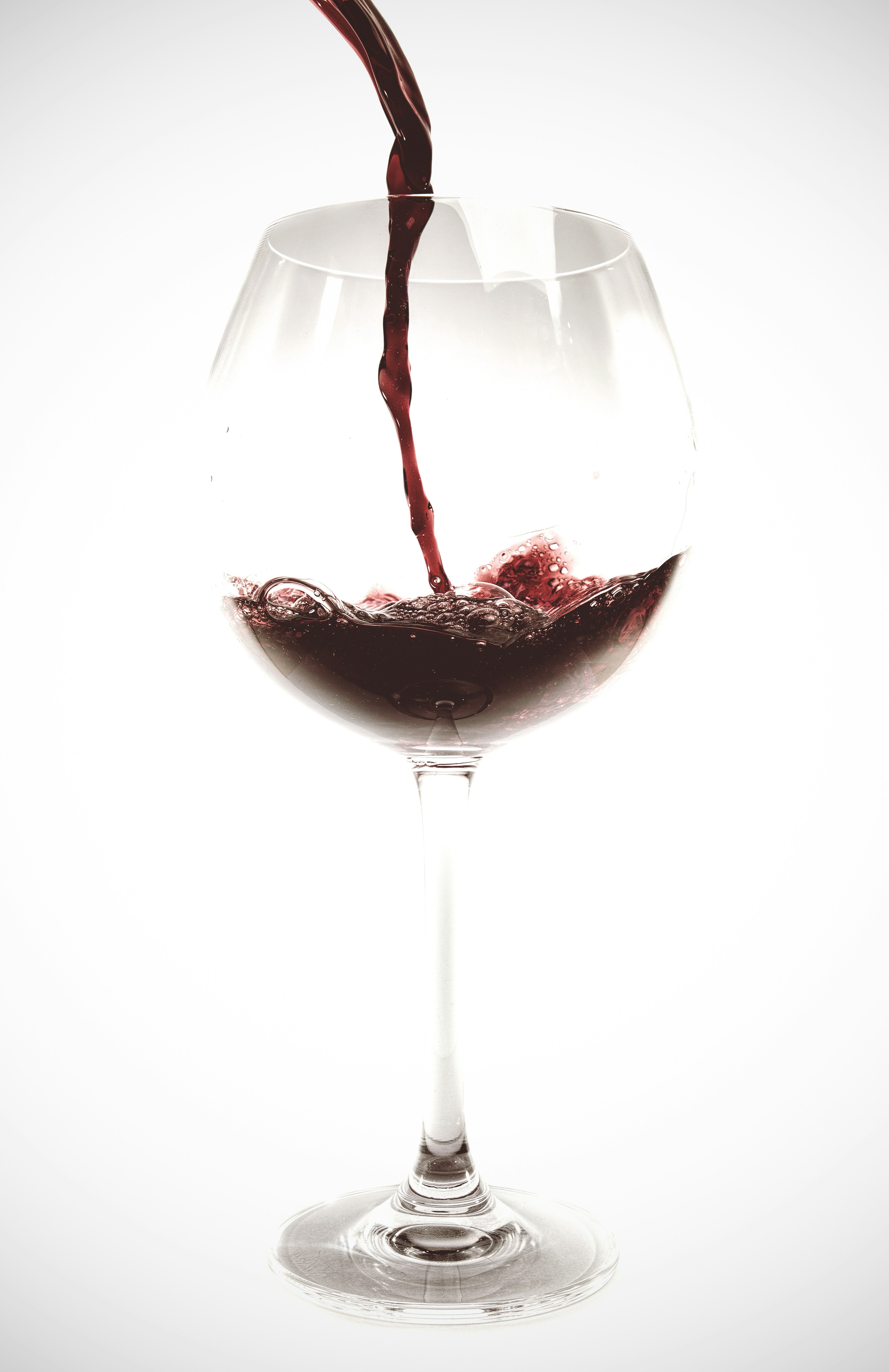 Elegant dark red wine in a crystal glass against a softly lit white background