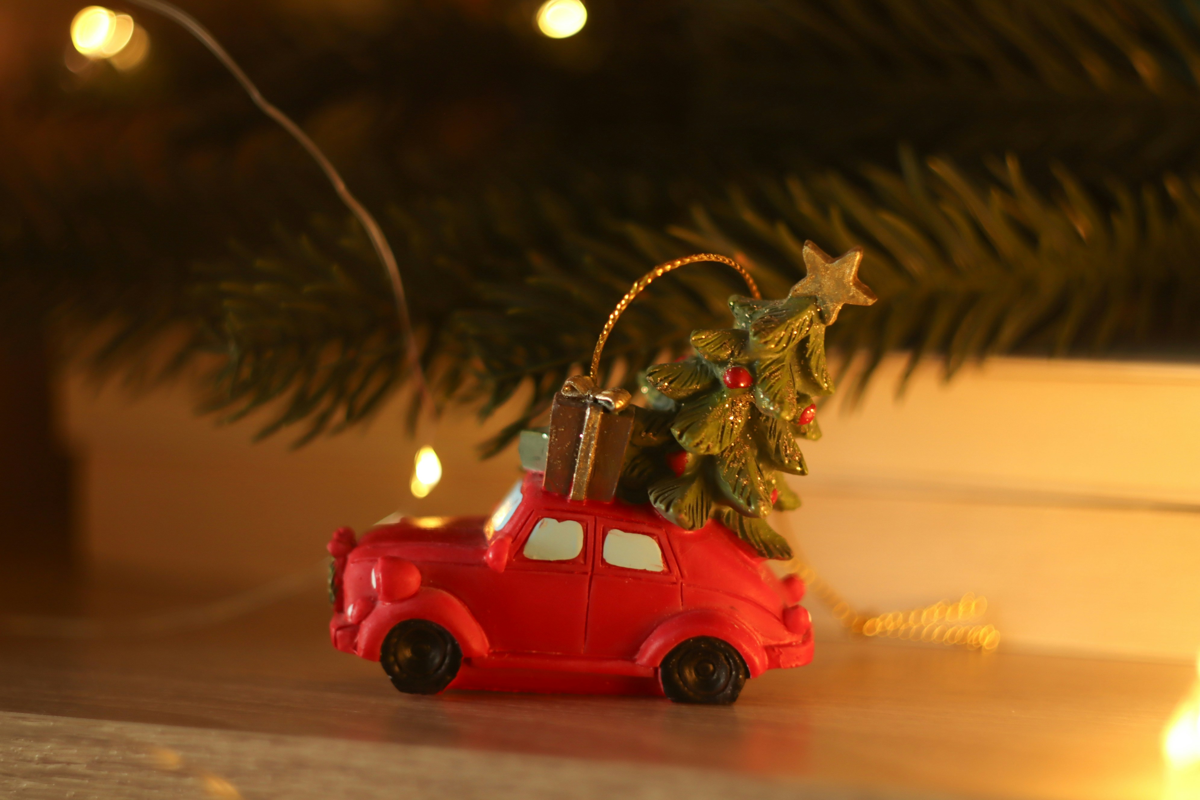 A red toy car carrying a christmas tree