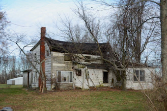 An old run down house in the middle of a field