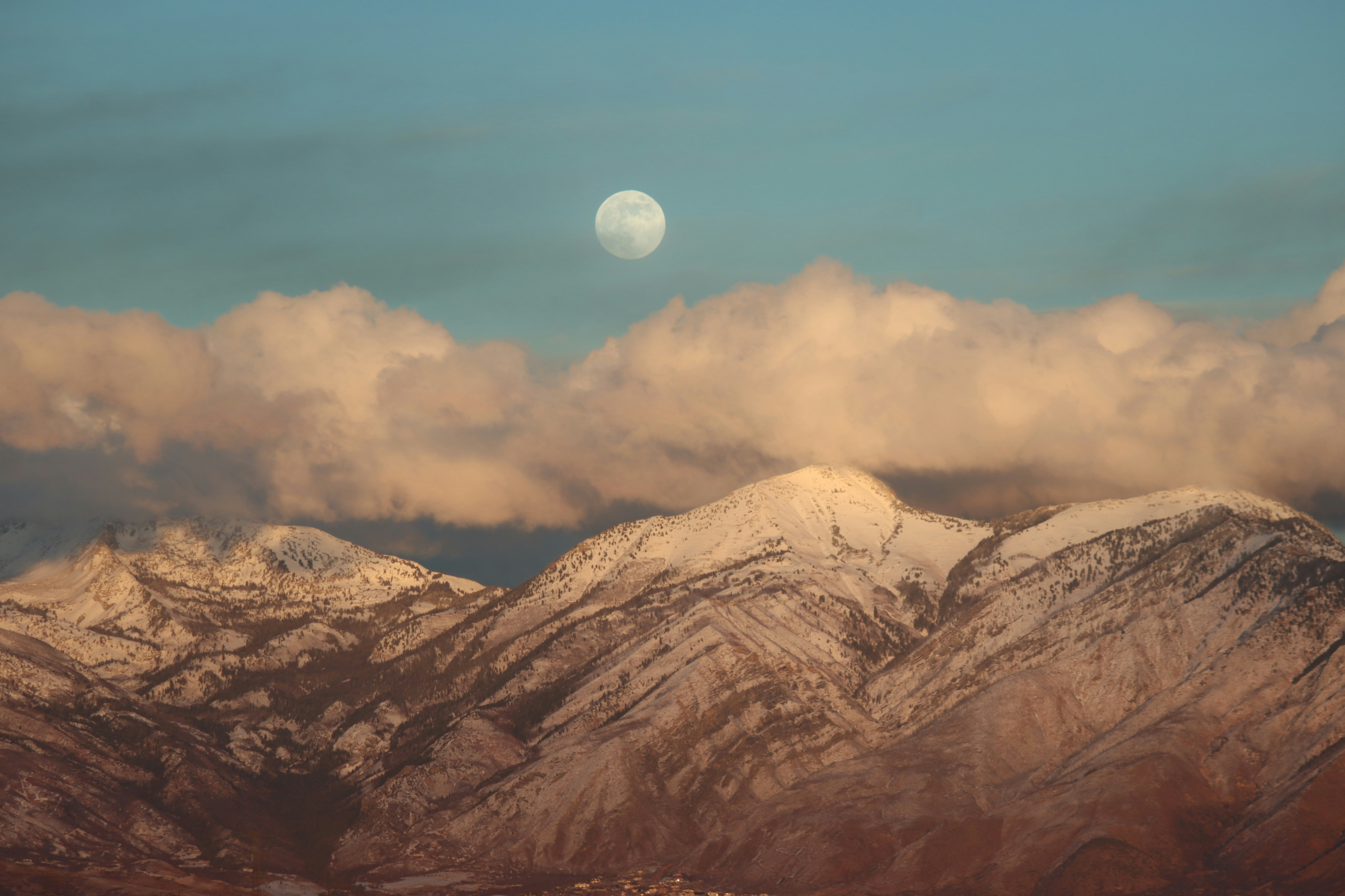 A view of a mountain range with a full moon in the distance