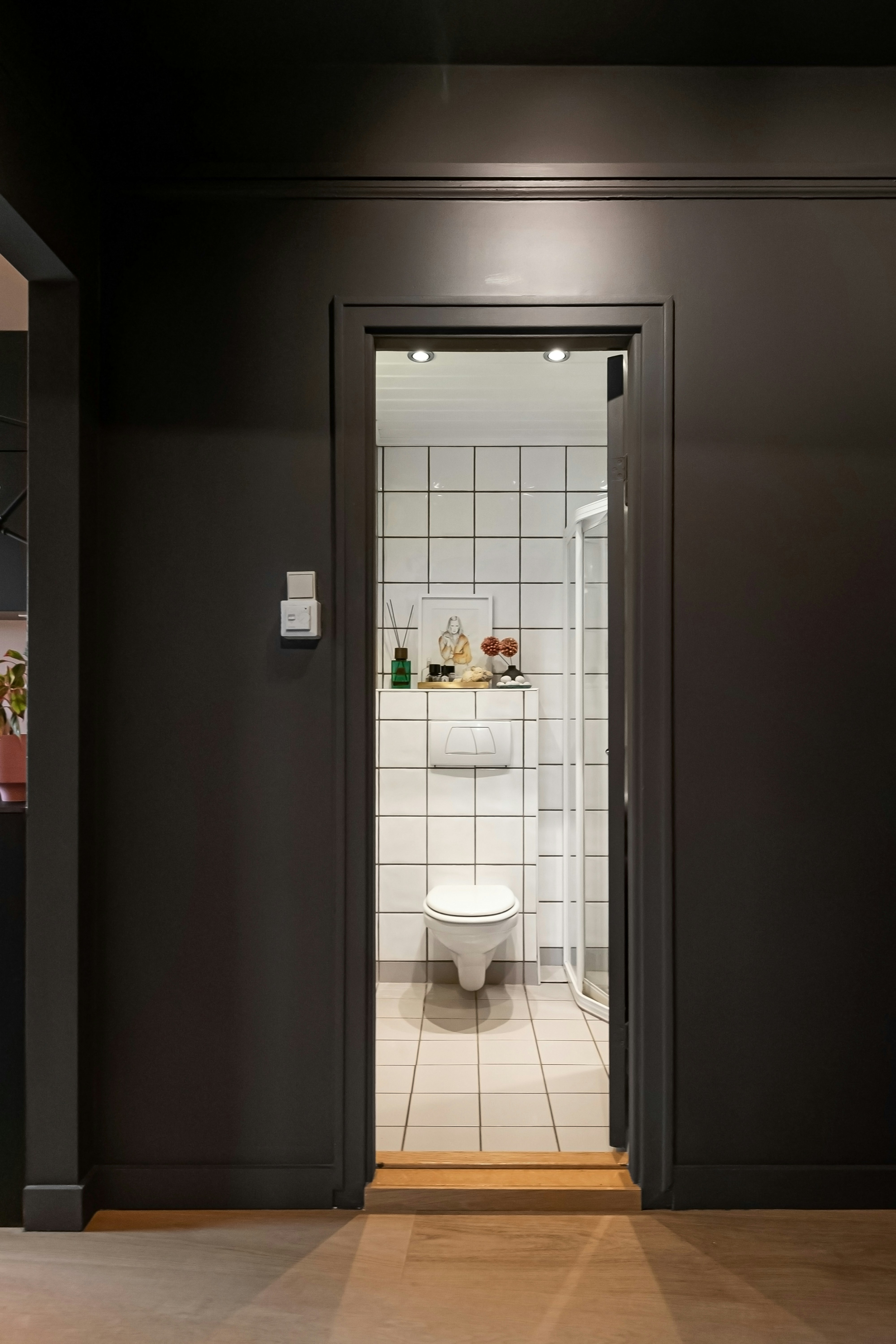 Eine weiße Toilette, die in einem Badezimmer neben einer ebenerdigen Dusche steht