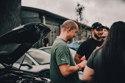 A group of people standing around a parked car
