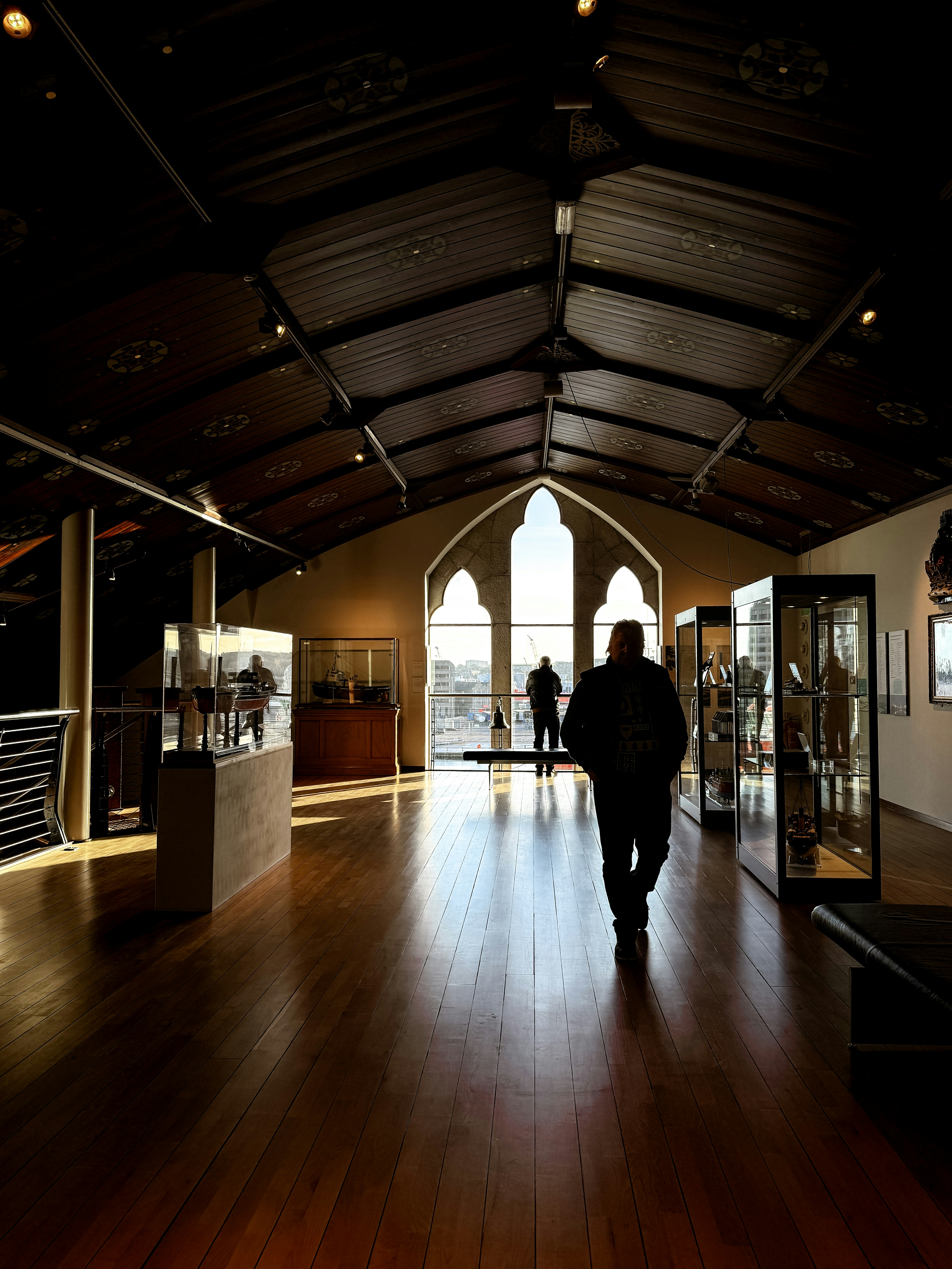 A person walking in a large room with wooden floors