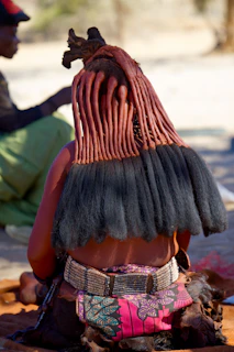 A woman sitting on the ground with a hat on her head