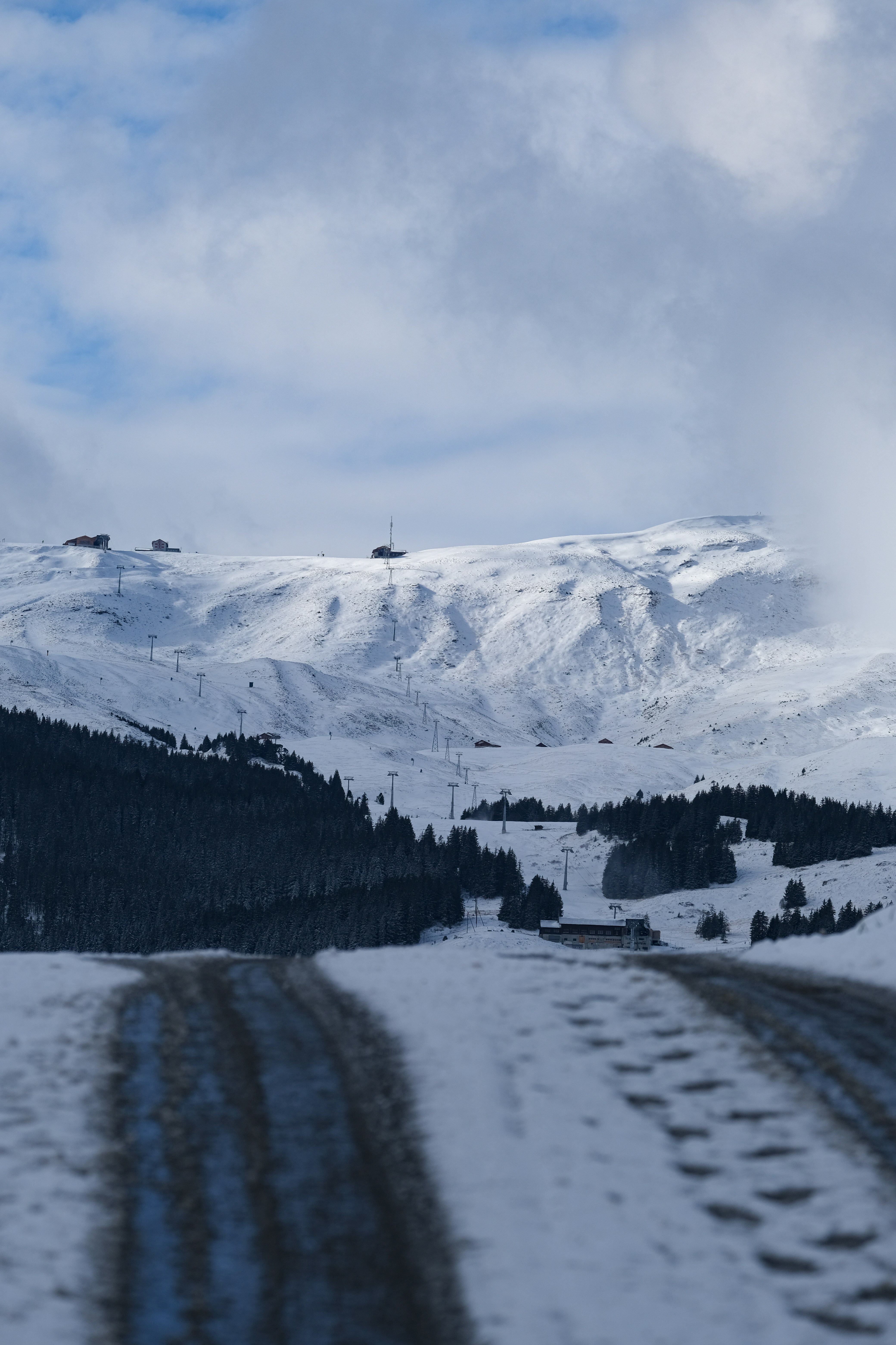 A snow covered road with a mountain in the background