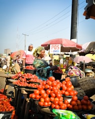 A group of people standing around a table filled with tomatoes