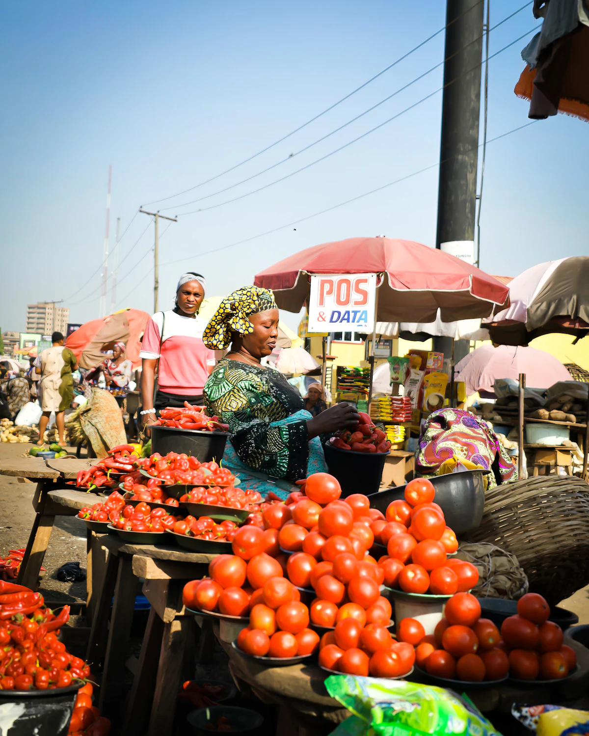 Community members gathered around a table of produce at a Nigerian market