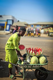 A man pushing a wheelbarrow filled with watermelon