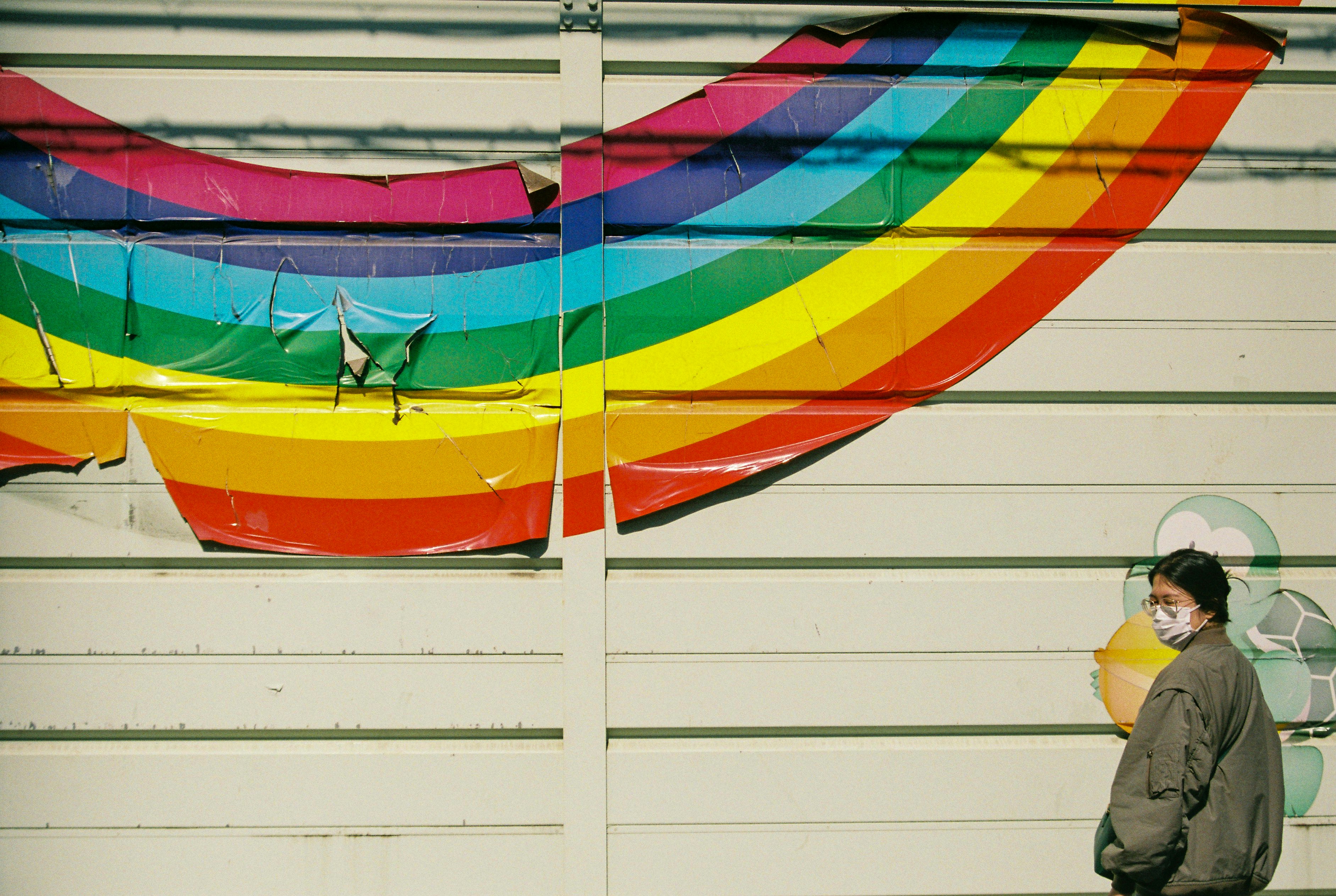 A man standing in front of a rainbow painted wall