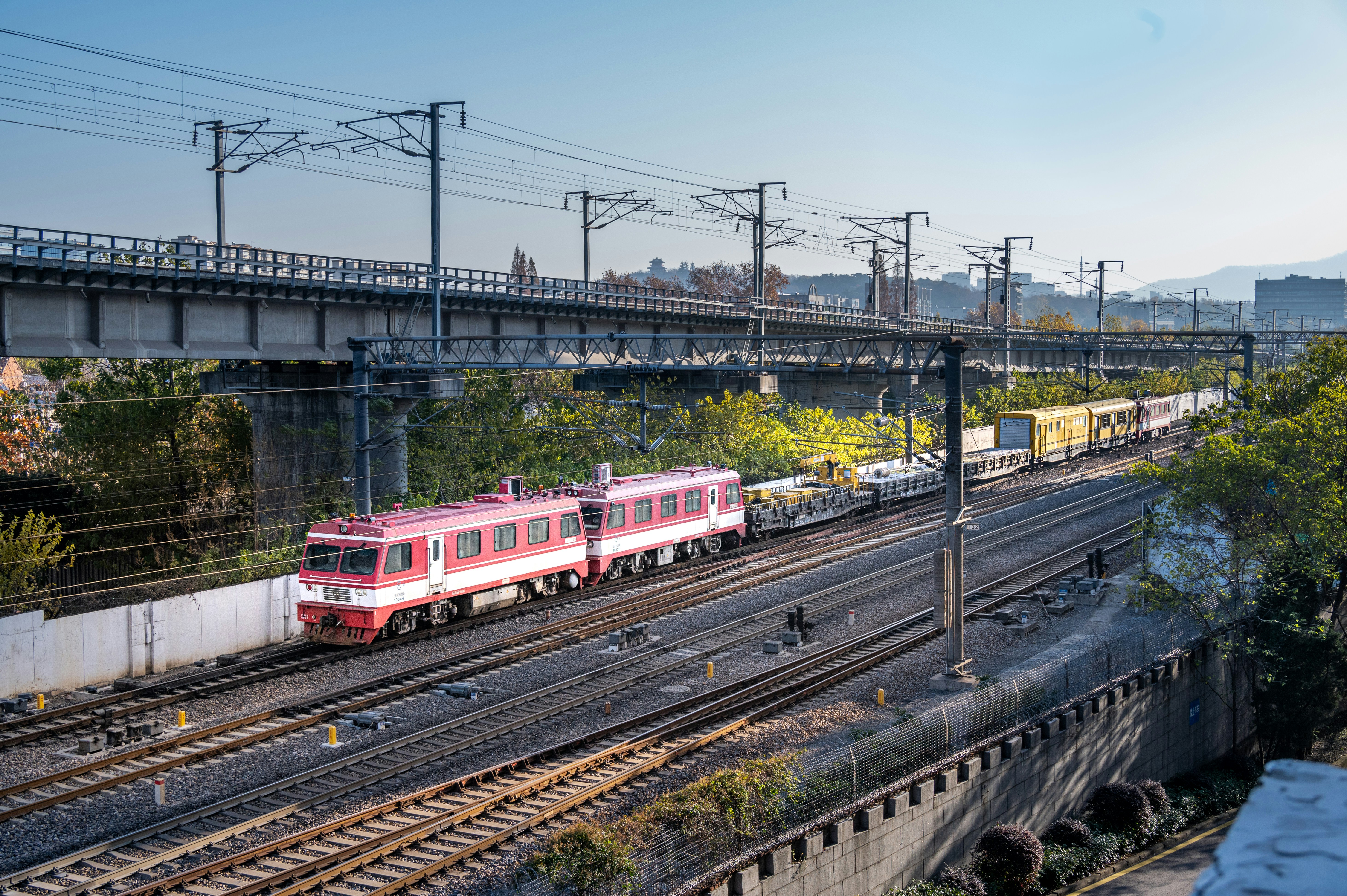 A red train traveling down train tracks next to a bridge