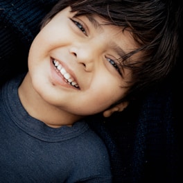 A young boy smiles while laying on his mother's lap