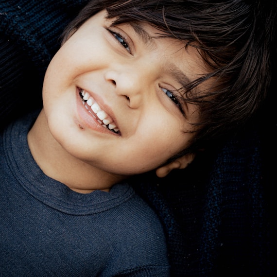 A young boy smiles while laying on his mother's lap