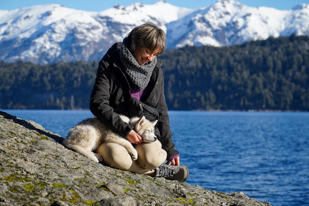 A woman sitting on a rock next to a dog