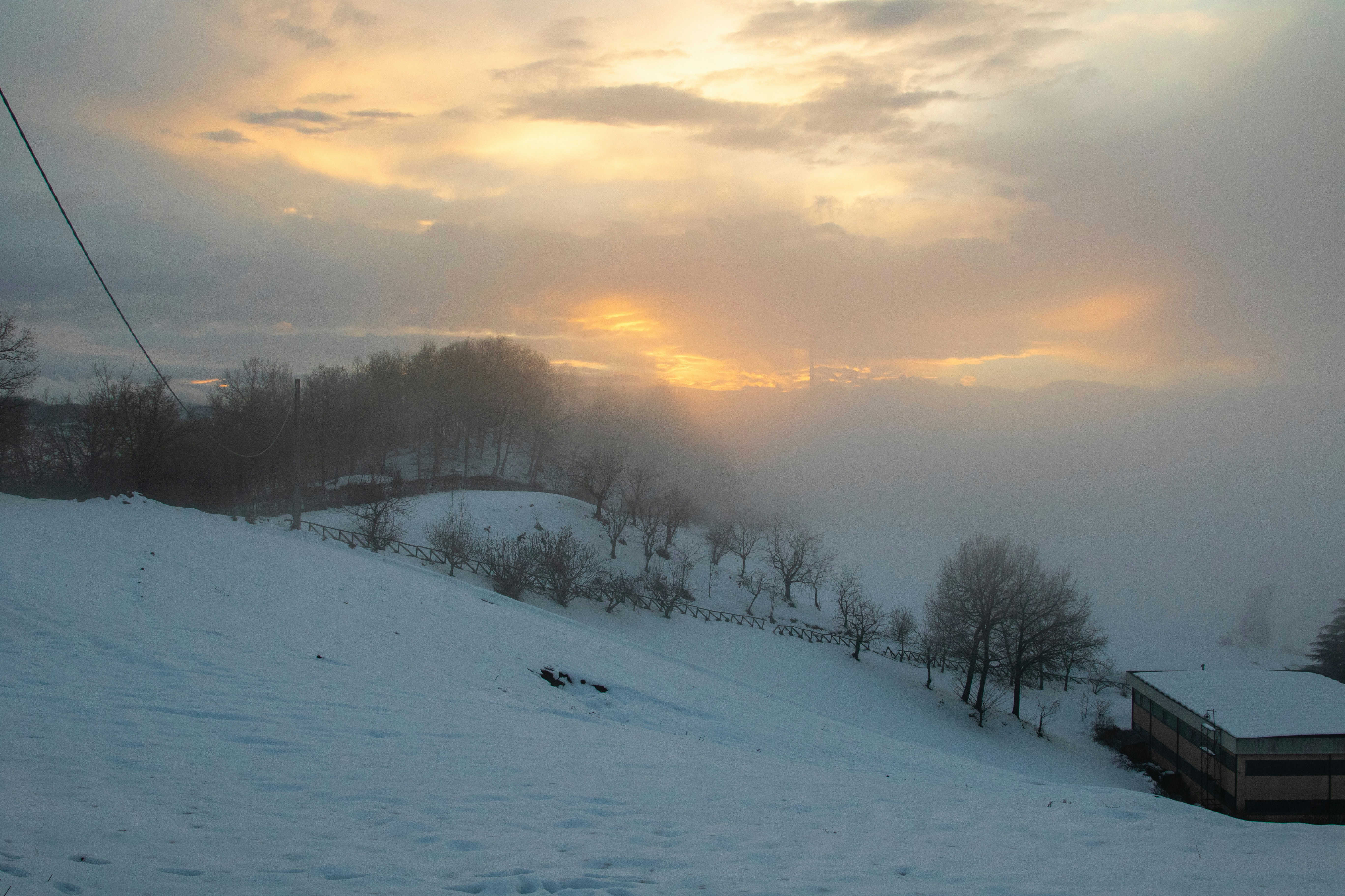 A snow covered hill with a ski lift in the distance