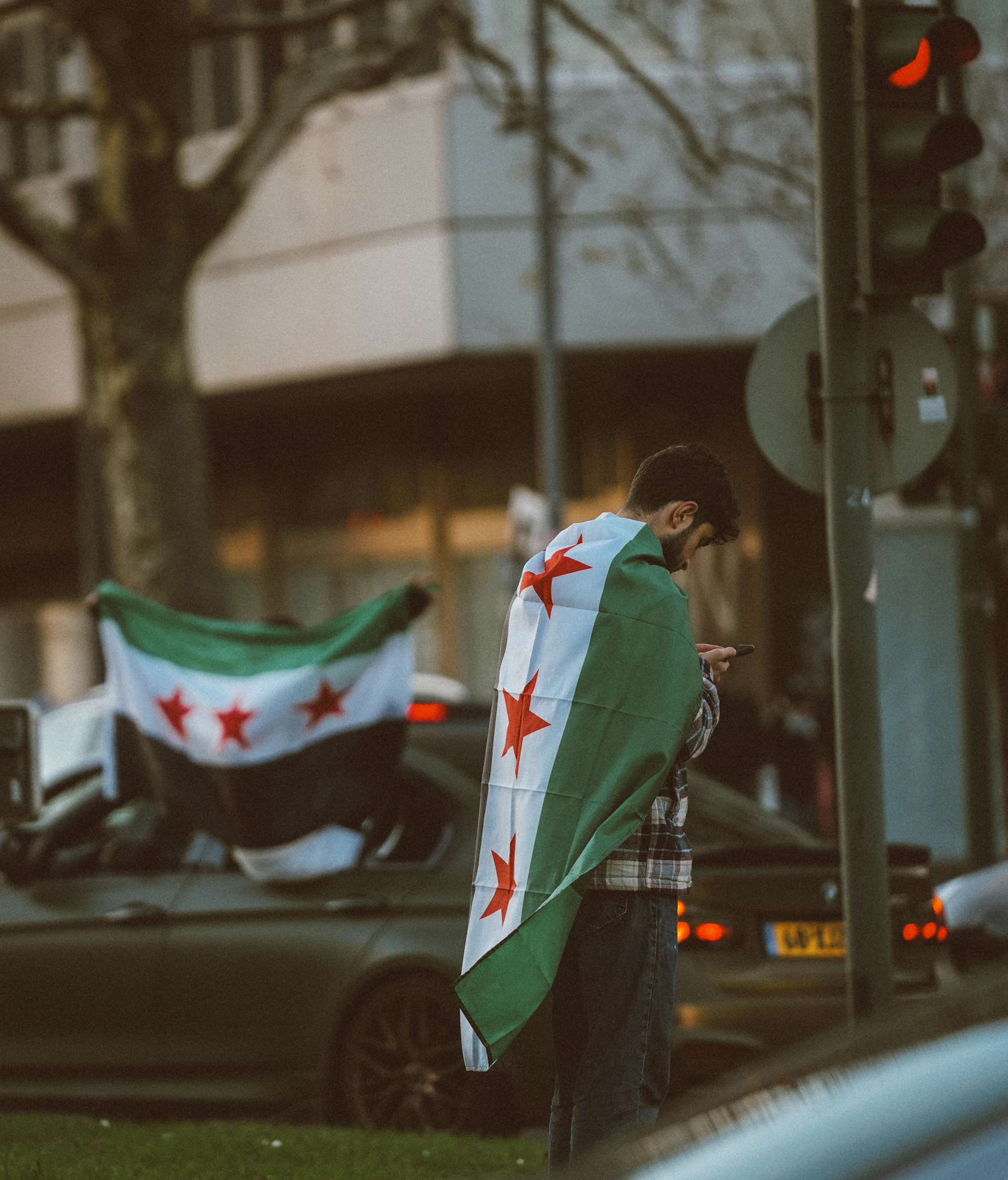 A man standing next to a car holding a flag