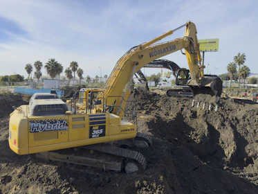 A large yellow excavator sitting on top of a pile of dirt