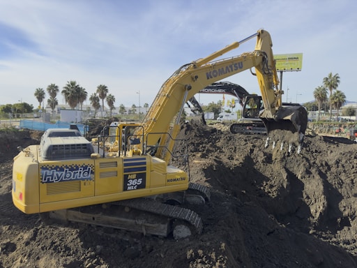 A large yellow excavator sitting on top of a pile of dirt