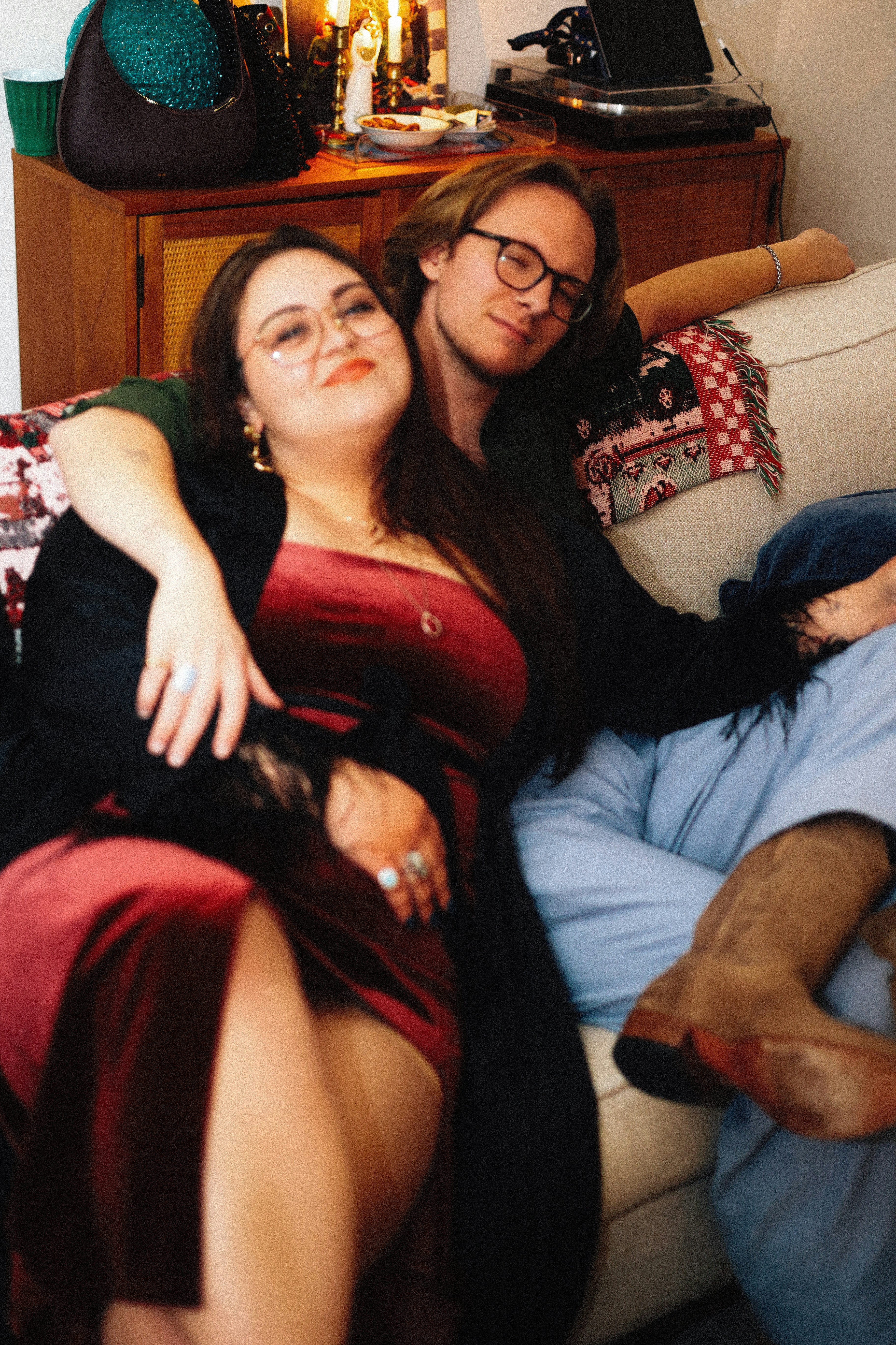 A couple comfortably poses together on a couch.