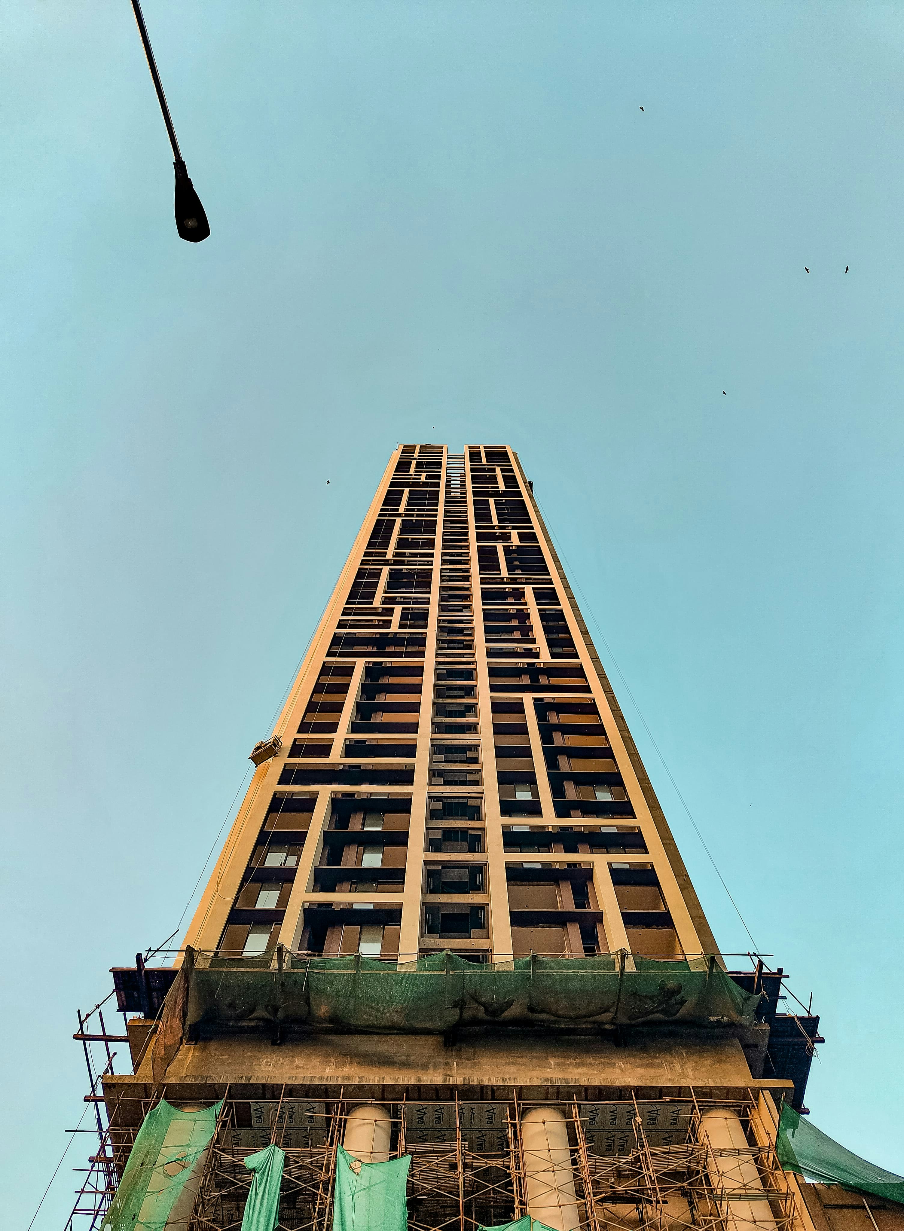 Modern building under construction featuring scaffolding and green safety netting.