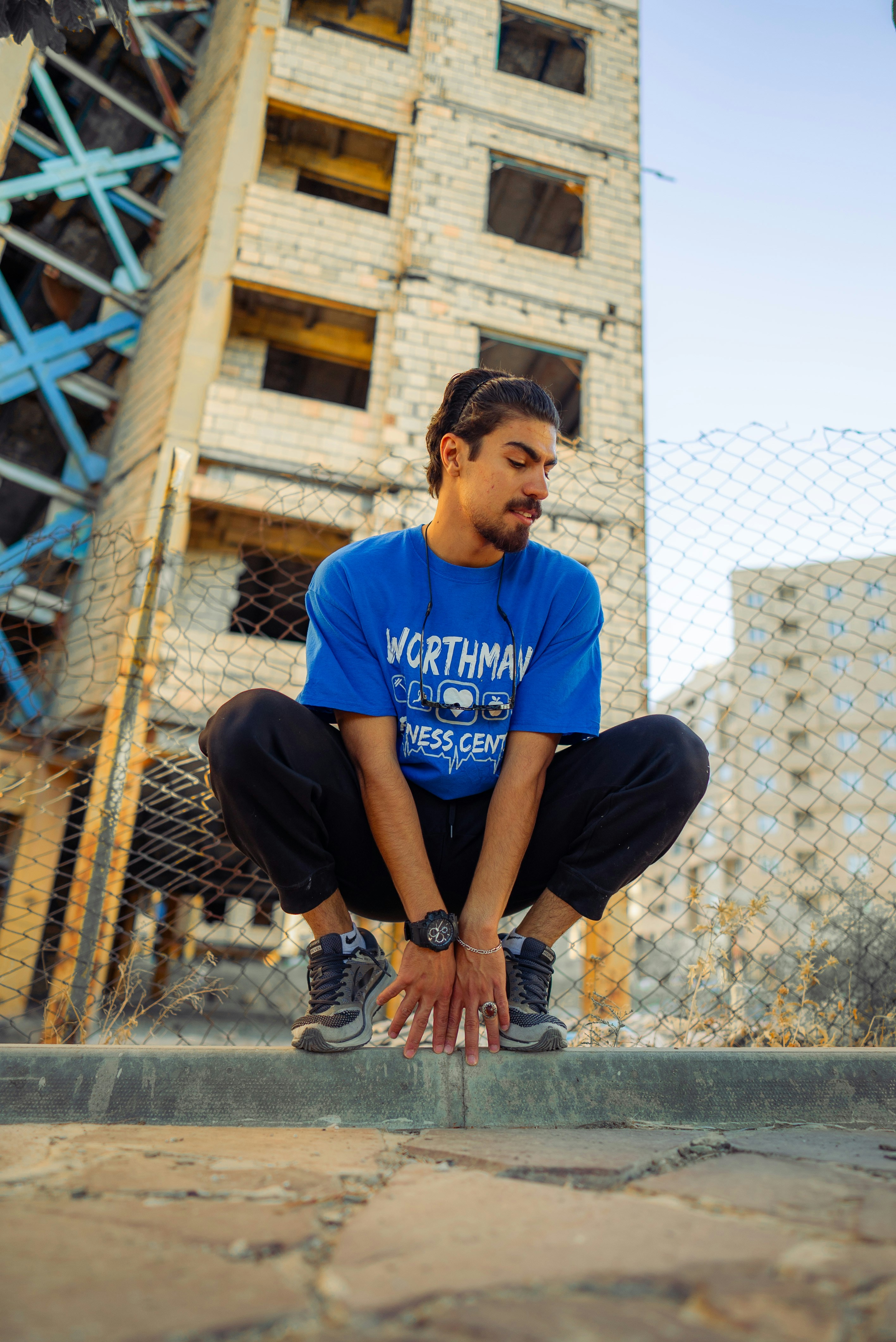 A man squatting down in front of a building