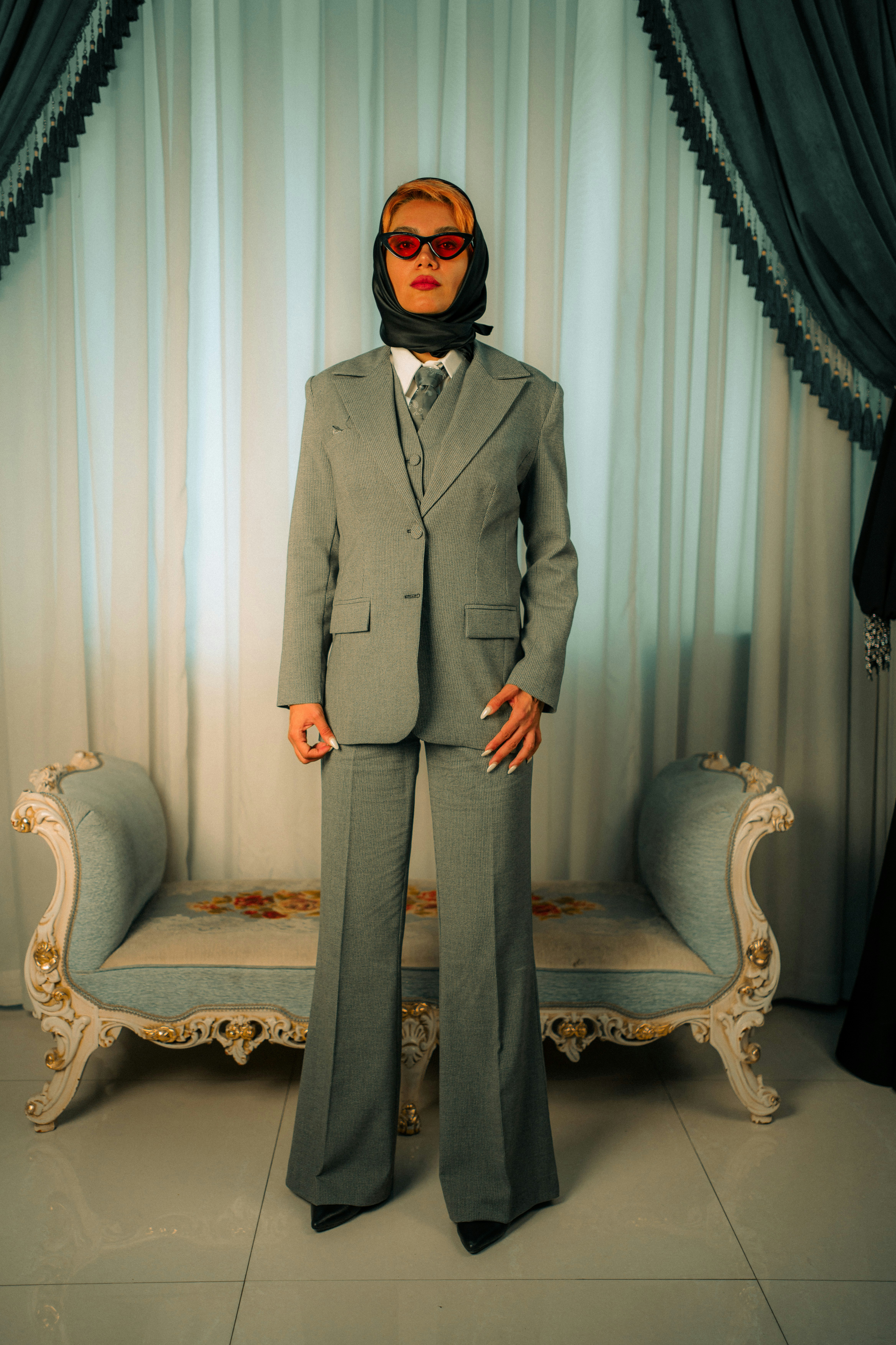 A man in a suit and tie standing in front of a couch