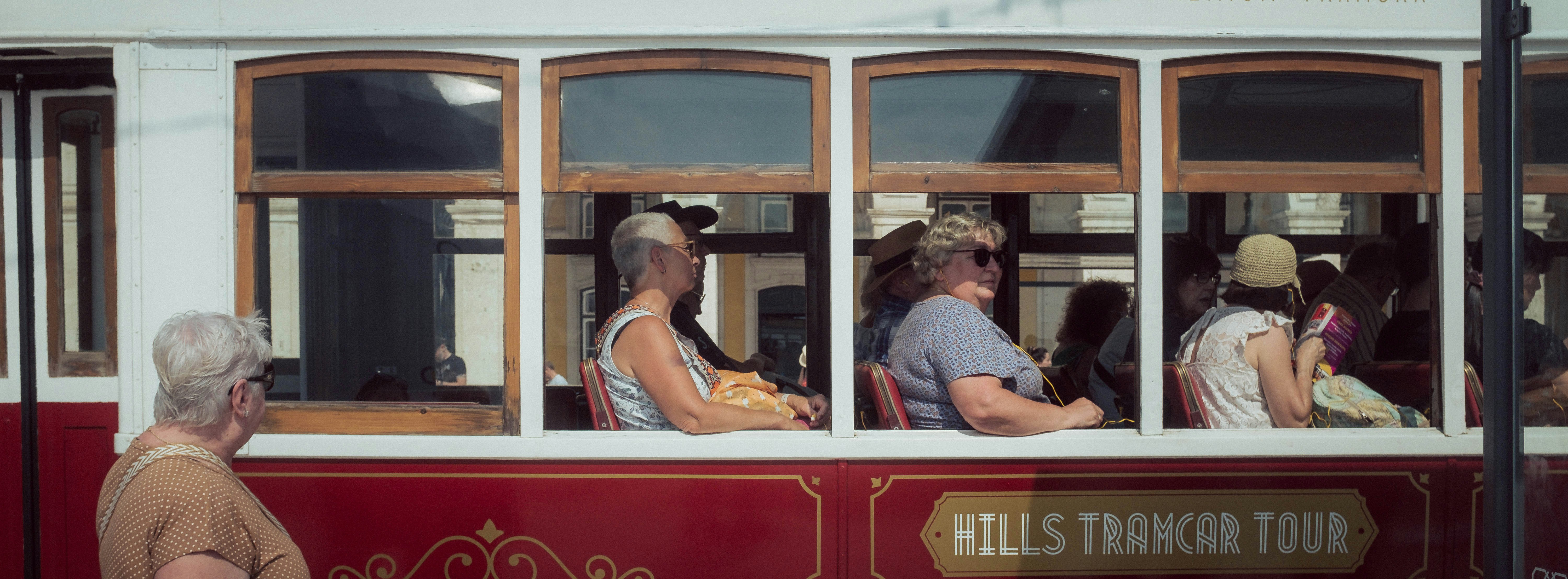 A group of people sitting on top of a red and white bus