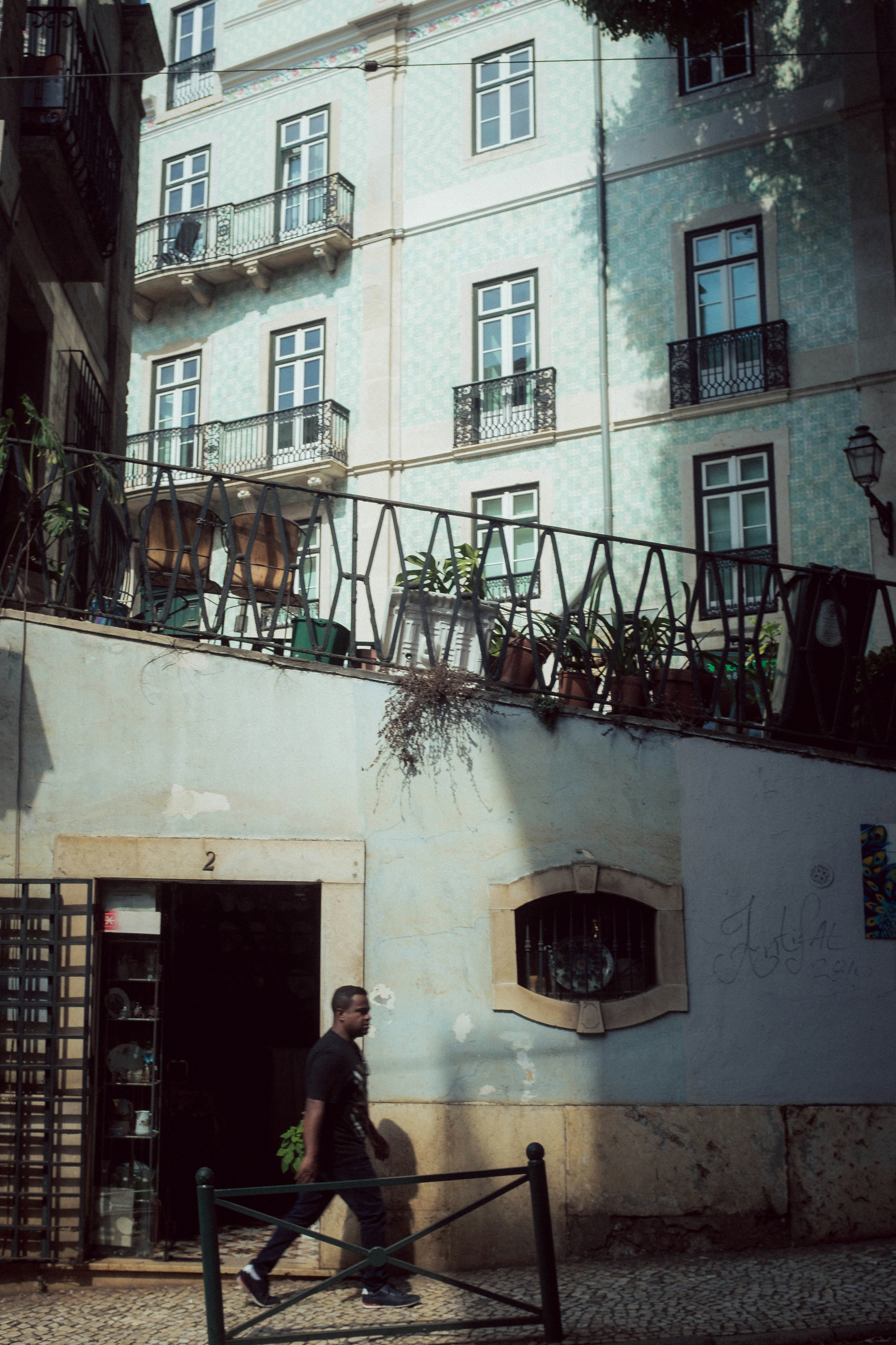 A man walking down a street past a tall building