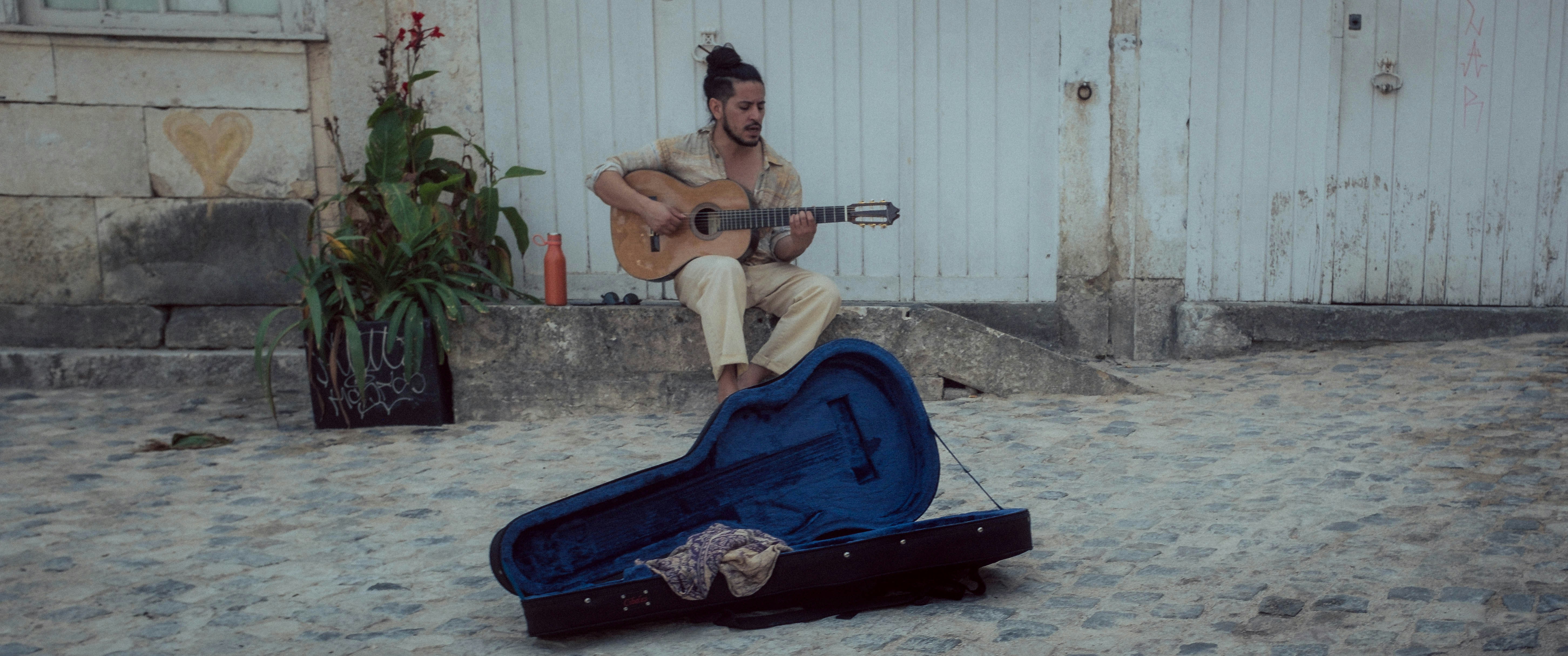 A man playing a guitar in front of a garage