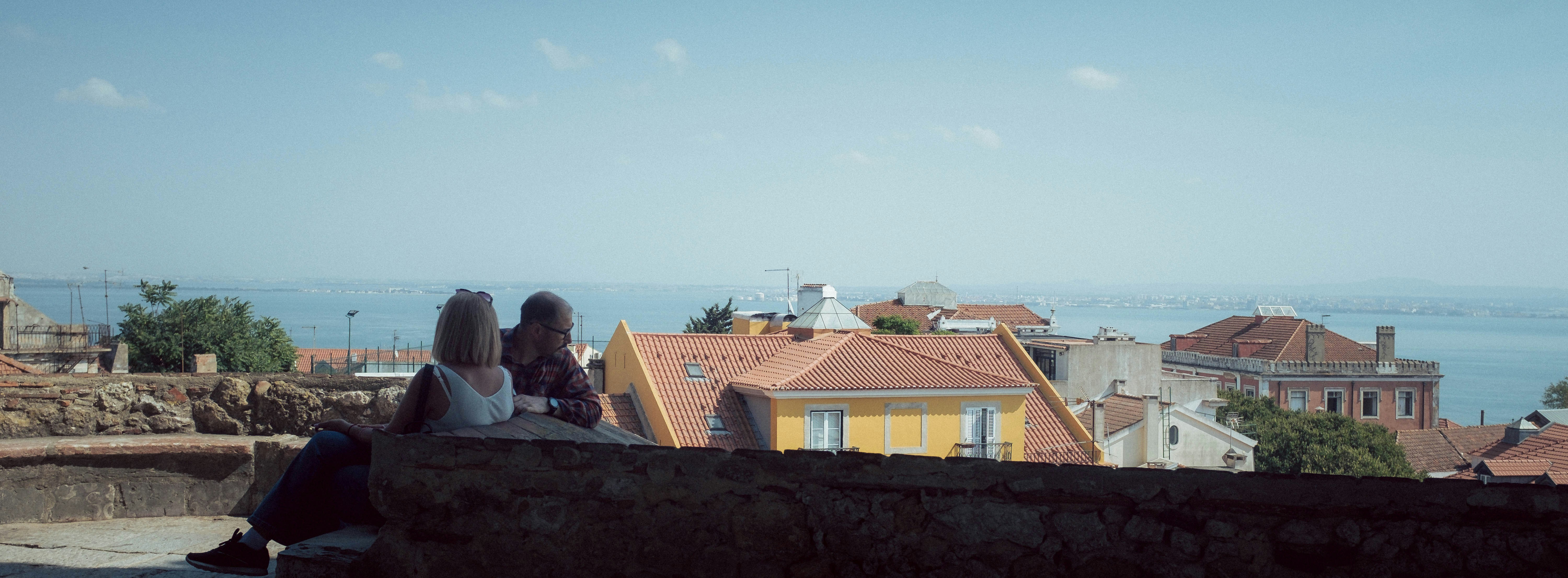 A couple of people sitting on top of a wall