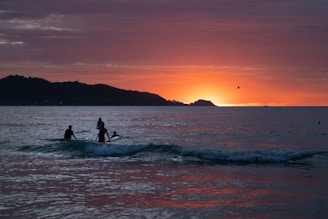 A couple of people riding a wave on top of a surfboard